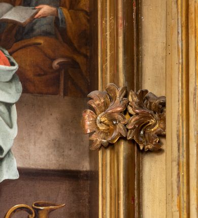 Zdjęcie nr 45: Nastawa architektoniczna, jednokondygnacyjna z glorią, jednoosiowa z bramkami, ustawiona na dwustrefowym cokole, na planie półowalu. Ołtarz kamienny, prostopadłościenny, z wcięciami na bocznych ściankach, zakończony profilowanym gzymsem; mensa kamienna. Na ściance frontowej namalowana scena Ostatniej Wieczerzy. Na ołtarzu ustawione drewniane tabernakulum obite blachą, w formie prostopadłościanu o wypukłych bokach, w narożach ujętego pilastrami o kanelowanych trzonach, dźwigającymi profilowany gzyms. Drzwiczki dwuskrzydłowe, w formie stojącego prostokąta zamkniętego łukiem półkolistym nadwieszonym, ujęty ramą z przedstawieniem baranka stojącego na ołtarzu, z którego piersi wypływa krew do kielicha; w górnej części monogram IHS. Nastawa ujęta dwiema parami filarów ustawionych pod kątem, o kanelowanych trzonach, dekorowanych kampanulami, podtrzymujących pełne belkowanie wyłamane na ich osi, z silnie wysuniętym gzymsem. Fryz zdobiony ornamentem roślinnym, w jego centrum kartusz z napisem „SANCTVS”. Na belkowaniu fragmenty zdwojonego, półkolistego przyczółka, z siedzącymi puttami. Pole główne wypełnione wnęką w formie stojącego prostokąta zamkniętego łukiem półkolistym nadwieszonym, ujęta profilowaną ramą, z obrazem Narodzenia Najświętszej Marii Panny. W przyłuczach dekoracja roślinna. Nastawa flankowana uszami utworzonymi z karbowanej wstęgi i ornamentu roślinnego. W miejscu zwieńczenia gołębica Ducha Świętego w otoku z obłoków i uskrzydlonych główek anielskich, w glorii promienistej. Bramki z drzwiczkami w formie stojącego prostokąta o wklęsłych górnych narożach ze ślimacznicami, ujęte grubą opaską, zwieńczone kluczem z herbem Uniwersytetu Jagiellońskiego oraz fragmentem profilowanego gzymsu, który stanowi podstawę dla figur św. Anny i św. Joachima. Herb lewej bramki z syglami „M[atthaeus] F[ranciscus]  K[alewski] / D[ecanus] S[antae] A[nnae] / C[uratus] Z[elenensis]”, herb prawej bramki z inskrypcją „A[NNO] D[OMINI] / 17/28”. Struktura w całości złocona, detale glorii srebrzone. Na odwrocie nastawy inskrypcja: „ODNOWIONO OŁTARZ ZA STARANIEM / KS(IĘDZA) JANA MICHALIKA. R(OKU) 1902.”