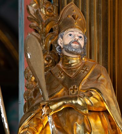 Zdjęcie nr 7: Nastawa architektoniczna, jednoosiowa, dwukondygnacyjna. Ołtarz prostopadłościenny, zwężający się ku dołowi, murowany, obłożony kamiennymi płytami, z krzyżem na froncie. 
Nastawa na niskim cokole, z wyodrębnionymi dwoma, ukośnie ustawionymi prostopadłościanami, z konsolami, dekorowanymi akantem i kampanulami. Pośrodku cokołu wyodrębniony postument dekorowany płyciną z akantem. Kondygnacja flankowana dwiema parami pilastrów o kanelowanych trzonach oraz ustawioną przed nimi parą kolumn o kapitelach kompozytowych. Podpory dźwigają pełne belkowanie, wyłamane na ich osi, z silnie wysuniętym gzymsem, z przerwanym architrawem i fryzem nad polem środkowym. Na belkowaniu fragmenty przerwanego, wolutowego przyczółka, zwrócone pod kątem, do wewnątrz. W polu środkowym wnęka w formie stojącego prostokąta zamkniętego łukiem półkolistym, ujęta profilowaną ramą dekorowaną na bokach kwiatami, zwieńczoną muszlą. We wnęce obraz św. Józefa z Dzieciątkiem. Poniżej wnęki płaskorzeźbione narzędzia stolarskie (piła, siekiera, kątownik, obcęgi) i stylizowany monogram świętego. Na konsolach, po bokach nastawy ustawione figury św. Wojciecha i św. Stanisława. Retabulum flankowane uszami utworzonymi z karbowanej wstęgi i ornamentu roślinnego. Druga kondygnacja węższa, ujęta ustawionymi pod kątem pilastrami, o trzonach dekorowanych kampanulami. Pilastry podtrzymują gzyms wyłamany na ich osi, nad polem przyjmujący kształt łuku półkolistego nadwieszonego. Na nim ustawione trzy wazony z kwiatami. W polu obraz św. Jana Kantego w formie stojącego owalu, ujęty ramą, dekorowaną ornamentem roślinnym. Struktura niemal w całości złocona, elementy cokołu i fryzu polichromowane w kolorze czerwonym, ornamentyka złocona. 
