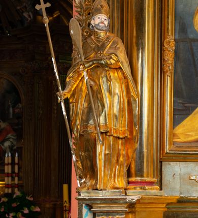 Zdjęcie nr 8: Nastawa architektoniczna, jednoosiowa, dwukondygnacyjna. Ołtarz prostopadłościenny, zwężający się ku dołowi, murowany, obłożony kamiennymi płytami, z krzyżem na froncie. 
Nastawa na niskim cokole, z wyodrębnionymi dwoma, ukośnie ustawionymi prostopadłościanami, z konsolami, dekorowanymi akantem i kampanulami. Pośrodku cokołu wyodrębniony postument dekorowany płyciną z akantem. Kondygnacja flankowana dwiema parami pilastrów o kanelowanych trzonach oraz ustawioną przed nimi parą kolumn o kapitelach kompozytowych. Podpory dźwigają pełne belkowanie, wyłamane na ich osi, z silnie wysuniętym gzymsem, z przerwanym architrawem i fryzem nad polem środkowym. Na belkowaniu fragmenty przerwanego, wolutowego przyczółka, zwrócone pod kątem, do wewnątrz. W polu środkowym wnęka w formie stojącego prostokąta zamkniętego łukiem półkolistym, ujęta profilowaną ramą dekorowaną na bokach kwiatami, zwieńczoną muszlą. We wnęce obraz św. Józefa z Dzieciątkiem. Poniżej wnęki płaskorzeźbione narzędzia stolarskie (piła, siekiera, kątownik, obcęgi) i stylizowany monogram świętego. Na konsolach, po bokach nastawy ustawione figury św. Wojciecha i św. Stanisława. Retabulum flankowane uszami utworzonymi z karbowanej wstęgi i ornamentu roślinnego. Druga kondygnacja węższa, ujęta ustawionymi pod kątem pilastrami, o trzonach dekorowanych kampanulami. Pilastry podtrzymują gzyms wyłamany na ich osi, nad polem przyjmujący kształt łuku półkolistego nadwieszonego. Na nim ustawione trzy wazony z kwiatami. W polu obraz św. Jana Kantego w formie stojącego owalu, ujęty ramą, dekorowaną ornamentem roślinnym. Struktura niemal w całości złocona, elementy cokołu i fryzu polichromowane w kolorze czerwonym, ornamentyka złocona. 
