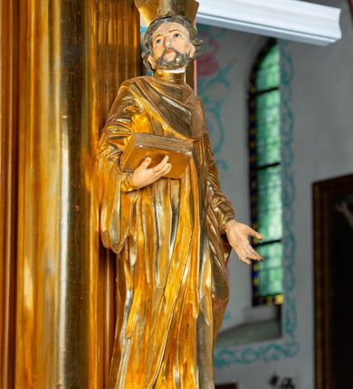 Zdjęcie nr 4: Nastawa architektoniczna, jednoosiowa, dwukondygnacyjna. Ołtarz murowany, prostopadłościenny, obity metalową blachą, zdobioną trybowaną kratownicą i gwiazdkami. Wewnątrz grób Chrystusa ze współczesną rzeźbą. Nastawa na niskim cokole, z wyodrębnionymi dwoma, ukośnie ustawionymi prostopadłościanami, z konsolami, dekorowanymi akantem i kampanulami. Pośrodku cokołu zamontowany obraz św. Faustyny w kształcie wieloboku. Kondygnacja flankowana dwiema parami pilastrów o kanelowanych trzonach oraz ustawioną przed nimi parą kolumn o kapitelach kompozytowych. Podpory dźwigają pełne belkowanie, wyłamane na ich osi, z silnie wysuniętym gzymsem, z przerwanym architrawem i fryzem nad polem środkowym. Na belkowaniu fragmenty przerwanego, wolutowego przyczółka, zwrócone pod kątem, do wewnątrz. W polu środkowym wnęka w formie stojącego prostokąta zamkniętego łukiem półkolistym, ujęta profilowaną ramą dekorowaną na bokach kwiatami, zwieńczoną muszlą. We wnęce obraz „Jezu Ufam Tobie”. Na konsolach, po bokach nastawy ustawione figury św. Kazimierza i św. Jana Kantego. Nastawa flankowana uszami utworzonymi z karbowanej wstęgi i ornamentu roślinnego. Druga kondygnacja węższa, flankowana ustawionymi pod kątem pilastrami, o trzonach dekorowanych kampanulami. Pilastry podtrzymują gzyms wyłamany na ich osi, nad polem przyjmujący kształt łuku półkolistego nadwieszonego. Na nim ustawione dwa wazony z kwiatami i bukiet kwiatów. W polu obraz św. Joachima w formie stojącego owalu, ujęty ramą, dekorowaną ornamentem roślinnym. Struktura niemal w całości złocona, elementy cokołu i fryzu polichromowane w kolorze czerwonym, ornamentyka złocona. 


