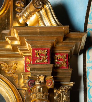 Zdjęcie nr 9: Nastawa architektoniczna, jednoosiowa, dwukondygnacyjna. Ołtarz murowany, prostopadłościenny, obity metalową blachą, zdobioną trybowaną kratownicą i gwiazdkami. Wewnątrz grób Chrystusa ze współczesną rzeźbą. Nastawa na niskim cokole, z wyodrębnionymi dwoma, ukośnie ustawionymi prostopadłościanami, z konsolami, dekorowanymi akantem i kampanulami. Pośrodku cokołu zamontowany obraz św. Faustyny w kształcie wieloboku. Kondygnacja flankowana dwiema parami pilastrów o kanelowanych trzonach oraz ustawioną przed nimi parą kolumn o kapitelach kompozytowych. Podpory dźwigają pełne belkowanie, wyłamane na ich osi, z silnie wysuniętym gzymsem, z przerwanym architrawem i fryzem nad polem środkowym. Na belkowaniu fragmenty przerwanego, wolutowego przyczółka, zwrócone pod kątem, do wewnątrz. W polu środkowym wnęka w formie stojącego prostokąta zamkniętego łukiem półkolistym, ujęta profilowaną ramą dekorowaną na bokach kwiatami, zwieńczoną muszlą. We wnęce obraz „Jezu Ufam Tobie”. Na konsolach, po bokach nastawy ustawione figury św. Kazimierza i św. Jana Kantego. Nastawa flankowana uszami utworzonymi z karbowanej wstęgi i ornamentu roślinnego. Druga kondygnacja węższa, flankowana ustawionymi pod kątem pilastrami, o trzonach dekorowanych kampanulami. Pilastry podtrzymują gzyms wyłamany na ich osi, nad polem przyjmujący kształt łuku półkolistego nadwieszonego. Na nim ustawione dwa wazony z kwiatami i bukiet kwiatów. W polu obraz św. Joachima w formie stojącego owalu, ujęty ramą, dekorowaną ornamentem roślinnym. Struktura niemal w całości złocona, elementy cokołu i fryzu polichromowane w kolorze czerwonym, ornamentyka złocona. 


