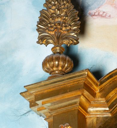 Zdjęcie nr 10: Nastawa architektoniczna, jednoosiowa, dwukondygnacyjna. Ołtarz murowany, prostopadłościenny, obity metalową blachą, zdobioną trybowaną kratownicą i gwiazdkami. Wewnątrz grób Chrystusa ze współczesną rzeźbą. Nastawa na niskim cokole, z wyodrębnionymi dwoma, ukośnie ustawionymi prostopadłościanami, z konsolami, dekorowanymi akantem i kampanulami. Pośrodku cokołu zamontowany obraz św. Faustyny w kształcie wieloboku. Kondygnacja flankowana dwiema parami pilastrów o kanelowanych trzonach oraz ustawioną przed nimi parą kolumn o kapitelach kompozytowych. Podpory dźwigają pełne belkowanie, wyłamane na ich osi, z silnie wysuniętym gzymsem, z przerwanym architrawem i fryzem nad polem środkowym. Na belkowaniu fragmenty przerwanego, wolutowego przyczółka, zwrócone pod kątem, do wewnątrz. W polu środkowym wnęka w formie stojącego prostokąta zamkniętego łukiem półkolistym, ujęta profilowaną ramą dekorowaną na bokach kwiatami, zwieńczoną muszlą. We wnęce obraz „Jezu Ufam Tobie”. Na konsolach, po bokach nastawy ustawione figury św. Kazimierza i św. Jana Kantego. Nastawa flankowana uszami utworzonymi z karbowanej wstęgi i ornamentu roślinnego. Druga kondygnacja węższa, flankowana ustawionymi pod kątem pilastrami, o trzonach dekorowanych kampanulami. Pilastry podtrzymują gzyms wyłamany na ich osi, nad polem przyjmujący kształt łuku półkolistego nadwieszonego. Na nim ustawione dwa wazony z kwiatami i bukiet kwiatów. W polu obraz św. Joachima w formie stojącego owalu, ujęty ramą, dekorowaną ornamentem roślinnym. Struktura niemal w całości złocona, elementy cokołu i fryzu polichromowane w kolorze czerwonym, ornamentyka złocona. 


