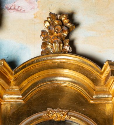 Zdjęcie nr 18: Nastawa architektoniczna, jednoosiowa, dwukondygnacyjna. Ołtarz murowany, prostopadłościenny, obity metalową blachą, zdobioną trybowaną kratownicą i gwiazdkami. Wewnątrz grób Chrystusa ze współczesną rzeźbą. Nastawa na niskim cokole, z wyodrębnionymi dwoma, ukośnie ustawionymi prostopadłościanami, z konsolami, dekorowanymi akantem i kampanulami. Pośrodku cokołu zamontowany obraz św. Faustyny w kształcie wieloboku. Kondygnacja flankowana dwiema parami pilastrów o kanelowanych trzonach oraz ustawioną przed nimi parą kolumn o kapitelach kompozytowych. Podpory dźwigają pełne belkowanie, wyłamane na ich osi, z silnie wysuniętym gzymsem, z przerwanym architrawem i fryzem nad polem środkowym. Na belkowaniu fragmenty przerwanego, wolutowego przyczółka, zwrócone pod kątem, do wewnątrz. W polu środkowym wnęka w formie stojącego prostokąta zamkniętego łukiem półkolistym, ujęta profilowaną ramą dekorowaną na bokach kwiatami, zwieńczoną muszlą. We wnęce obraz „Jezu Ufam Tobie”. Na konsolach, po bokach nastawy ustawione figury św. Kazimierza i św. Jana Kantego. Nastawa flankowana uszami utworzonymi z karbowanej wstęgi i ornamentu roślinnego. Druga kondygnacja węższa, flankowana ustawionymi pod kątem pilastrami, o trzonach dekorowanych kampanulami. Pilastry podtrzymują gzyms wyłamany na ich osi, nad polem przyjmujący kształt łuku półkolistego nadwieszonego. Na nim ustawione dwa wazony z kwiatami i bukiet kwiatów. W polu obraz św. Joachima w formie stojącego owalu, ujęty ramą, dekorowaną ornamentem roślinnym. Struktura niemal w całości złocona, elementy cokołu i fryzu polichromowane w kolorze czerwonym, ornamentyka złocona. 


