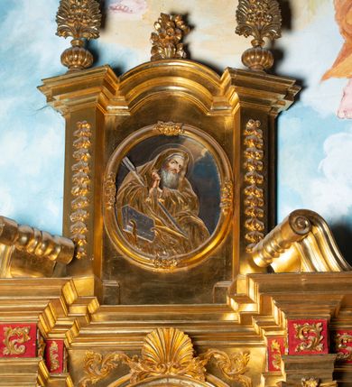 Zdjęcie nr 19: Nastawa architektoniczna, jednoosiowa, dwukondygnacyjna. Ołtarz murowany, prostopadłościenny, obity metalową blachą, zdobioną trybowaną kratownicą i gwiazdkami. Wewnątrz grób Chrystusa ze współczesną rzeźbą. Nastawa na niskim cokole, z wyodrębnionymi dwoma, ukośnie ustawionymi prostopadłościanami, z konsolami, dekorowanymi akantem i kampanulami. Pośrodku cokołu zamontowany obraz św. Faustyny w kształcie wieloboku. Kondygnacja flankowana dwiema parami pilastrów o kanelowanych trzonach oraz ustawioną przed nimi parą kolumn o kapitelach kompozytowych. Podpory dźwigają pełne belkowanie, wyłamane na ich osi, z silnie wysuniętym gzymsem, z przerwanym architrawem i fryzem nad polem środkowym. Na belkowaniu fragmenty przerwanego, wolutowego przyczółka, zwrócone pod kątem, do wewnątrz. W polu środkowym wnęka w formie stojącego prostokąta zamkniętego łukiem półkolistym, ujęta profilowaną ramą dekorowaną na bokach kwiatami, zwieńczoną muszlą. We wnęce obraz „Jezu Ufam Tobie”. Na konsolach, po bokach nastawy ustawione figury św. Kazimierza i św. Jana Kantego. Nastawa flankowana uszami utworzonymi z karbowanej wstęgi i ornamentu roślinnego. Druga kondygnacja węższa, flankowana ustawionymi pod kątem pilastrami, o trzonach dekorowanych kampanulami. Pilastry podtrzymują gzyms wyłamany na ich osi, nad polem przyjmujący kształt łuku półkolistego nadwieszonego. Na nim ustawione dwa wazony z kwiatami i bukiet kwiatów. W polu obraz św. Joachima w formie stojącego owalu, ujęty ramą, dekorowaną ornamentem roślinnym. Struktura niemal w całości złocona, elementy cokołu i fryzu polichromowane w kolorze czerwonym, ornamentyka złocona. 


