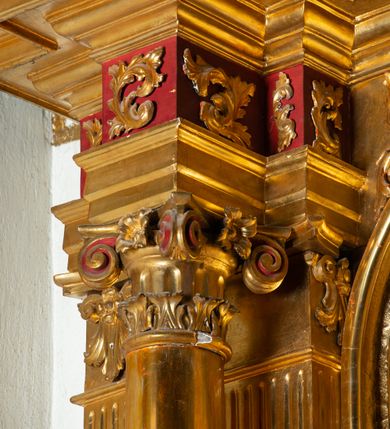 Zdjęcie nr 21: Nastawa architektoniczna, jednoosiowa, dwukondygnacyjna. Ołtarz murowany, prostopadłościenny, obity metalową blachą, zdobioną trybowaną kratownicą i gwiazdkami. Wewnątrz grób Chrystusa ze współczesną rzeźbą. Nastawa na niskim cokole, z wyodrębnionymi dwoma, ukośnie ustawionymi prostopadłościanami, z konsolami, dekorowanymi akantem i kampanulami. Pośrodku cokołu zamontowany obraz św. Faustyny w kształcie wieloboku. Kondygnacja flankowana dwiema parami pilastrów o kanelowanych trzonach oraz ustawioną przed nimi parą kolumn o kapitelach kompozytowych. Podpory dźwigają pełne belkowanie, wyłamane na ich osi, z silnie wysuniętym gzymsem, z przerwanym architrawem i fryzem nad polem środkowym. Na belkowaniu fragmenty przerwanego, wolutowego przyczółka, zwrócone pod kątem, do wewnątrz. W polu środkowym wnęka w formie stojącego prostokąta zamkniętego łukiem półkolistym, ujęta profilowaną ramą dekorowaną na bokach kwiatami, zwieńczoną muszlą. We wnęce obraz „Jezu Ufam Tobie”. Na konsolach, po bokach nastawy ustawione figury św. Kazimierza i św. Jana Kantego. Nastawa flankowana uszami utworzonymi z karbowanej wstęgi i ornamentu roślinnego. Druga kondygnacja węższa, flankowana ustawionymi pod kątem pilastrami, o trzonach dekorowanych kampanulami. Pilastry podtrzymują gzyms wyłamany na ich osi, nad polem przyjmujący kształt łuku półkolistego nadwieszonego. Na nim ustawione dwa wazony z kwiatami i bukiet kwiatów. W polu obraz św. Joachima w formie stojącego owalu, ujęty ramą, dekorowaną ornamentem roślinnym. Struktura niemal w całości złocona, elementy cokołu i fryzu polichromowane w kolorze czerwonym, ornamentyka złocona. 


