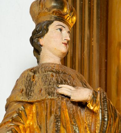 Zdjęcie nr 28: Nastawa architektoniczna, jednoosiowa, dwukondygnacyjna. Ołtarz murowany, prostopadłościenny, obity metalową blachą, zdobioną trybowaną kratownicą i gwiazdkami. Wewnątrz grób Chrystusa ze współczesną rzeźbą. Nastawa na niskim cokole, z wyodrębnionymi dwoma, ukośnie ustawionymi prostopadłościanami, z konsolami, dekorowanymi akantem i kampanulami. Pośrodku cokołu zamontowany obraz św. Faustyny w kształcie wieloboku. Kondygnacja flankowana dwiema parami pilastrów o kanelowanych trzonach oraz ustawioną przed nimi parą kolumn o kapitelach kompozytowych. Podpory dźwigają pełne belkowanie, wyłamane na ich osi, z silnie wysuniętym gzymsem, z przerwanym architrawem i fryzem nad polem środkowym. Na belkowaniu fragmenty przerwanego, wolutowego przyczółka, zwrócone pod kątem, do wewnątrz. W polu środkowym wnęka w formie stojącego prostokąta zamkniętego łukiem półkolistym, ujęta profilowaną ramą dekorowaną na bokach kwiatami, zwieńczoną muszlą. We wnęce obraz „Jezu Ufam Tobie”. Na konsolach, po bokach nastawy ustawione figury św. Kazimierza i św. Jana Kantego. Nastawa flankowana uszami utworzonymi z karbowanej wstęgi i ornamentu roślinnego. Druga kondygnacja węższa, flankowana ustawionymi pod kątem pilastrami, o trzonach dekorowanych kampanulami. Pilastry podtrzymują gzyms wyłamany na ich osi, nad polem przyjmujący kształt łuku półkolistego nadwieszonego. Na nim ustawione dwa wazony z kwiatami i bukiet kwiatów. W polu obraz św. Joachima w formie stojącego owalu, ujęty ramą, dekorowaną ornamentem roślinnym. Struktura niemal w całości złocona, elementy cokołu i fryzu polichromowane w kolorze czerwonym, ornamentyka złocona. 


