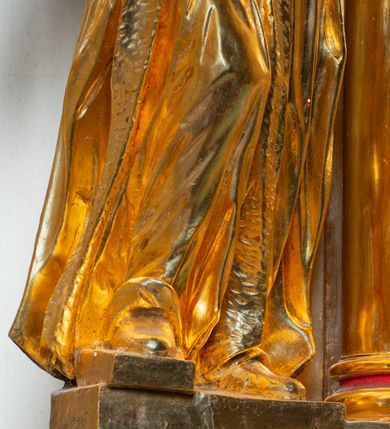 Zdjęcie nr 30: Nastawa architektoniczna, jednoosiowa, dwukondygnacyjna. Ołtarz murowany, prostopadłościenny, obity metalową blachą, zdobioną trybowaną kratownicą i gwiazdkami. Wewnątrz grób Chrystusa ze współczesną rzeźbą. Nastawa na niskim cokole, z wyodrębnionymi dwoma, ukośnie ustawionymi prostopadłościanami, z konsolami, dekorowanymi akantem i kampanulami. Pośrodku cokołu zamontowany obraz św. Faustyny w kształcie wieloboku. Kondygnacja flankowana dwiema parami pilastrów o kanelowanych trzonach oraz ustawioną przed nimi parą kolumn o kapitelach kompozytowych. Podpory dźwigają pełne belkowanie, wyłamane na ich osi, z silnie wysuniętym gzymsem, z przerwanym architrawem i fryzem nad polem środkowym. Na belkowaniu fragmenty przerwanego, wolutowego przyczółka, zwrócone pod kątem, do wewnątrz. W polu środkowym wnęka w formie stojącego prostokąta zamkniętego łukiem półkolistym, ujęta profilowaną ramą dekorowaną na bokach kwiatami, zwieńczoną muszlą. We wnęce obraz „Jezu Ufam Tobie”. Na konsolach, po bokach nastawy ustawione figury św. Kazimierza i św. Jana Kantego. Nastawa flankowana uszami utworzonymi z karbowanej wstęgi i ornamentu roślinnego. Druga kondygnacja węższa, flankowana ustawionymi pod kątem pilastrami, o trzonach dekorowanych kampanulami. Pilastry podtrzymują gzyms wyłamany na ich osi, nad polem przyjmujący kształt łuku półkolistego nadwieszonego. Na nim ustawione dwa wazony z kwiatami i bukiet kwiatów. W polu obraz św. Joachima w formie stojącego owalu, ujęty ramą, dekorowaną ornamentem roślinnym. Struktura niemal w całości złocona, elementy cokołu i fryzu polichromowane w kolorze czerwonym, ornamentyka złocona. 


