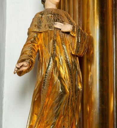 Zdjęcie nr 33: Nastawa architektoniczna, jednoosiowa, dwukondygnacyjna. Ołtarz murowany, prostopadłościenny, obity metalową blachą, zdobioną trybowaną kratownicą i gwiazdkami. Wewnątrz grób Chrystusa ze współczesną rzeźbą. Nastawa na niskim cokole, z wyodrębnionymi dwoma, ukośnie ustawionymi prostopadłościanami, z konsolami, dekorowanymi akantem i kampanulami. Pośrodku cokołu zamontowany obraz św. Faustyny w kształcie wieloboku. Kondygnacja flankowana dwiema parami pilastrów o kanelowanych trzonach oraz ustawioną przed nimi parą kolumn o kapitelach kompozytowych. Podpory dźwigają pełne belkowanie, wyłamane na ich osi, z silnie wysuniętym gzymsem, z przerwanym architrawem i fryzem nad polem środkowym. Na belkowaniu fragmenty przerwanego, wolutowego przyczółka, zwrócone pod kątem, do wewnątrz. W polu środkowym wnęka w formie stojącego prostokąta zamkniętego łukiem półkolistym, ujęta profilowaną ramą dekorowaną na bokach kwiatami, zwieńczoną muszlą. We wnęce obraz „Jezu Ufam Tobie”. Na konsolach, po bokach nastawy ustawione figury św. Kazimierza i św. Jana Kantego. Nastawa flankowana uszami utworzonymi z karbowanej wstęgi i ornamentu roślinnego. Druga kondygnacja węższa, flankowana ustawionymi pod kątem pilastrami, o trzonach dekorowanych kampanulami. Pilastry podtrzymują gzyms wyłamany na ich osi, nad polem przyjmujący kształt łuku półkolistego nadwieszonego. Na nim ustawione dwa wazony z kwiatami i bukiet kwiatów. W polu obraz św. Joachima w formie stojącego owalu, ujęty ramą, dekorowaną ornamentem roślinnym. Struktura niemal w całości złocona, elementy cokołu i fryzu polichromowane w kolorze czerwonym, ornamentyka złocona. 


