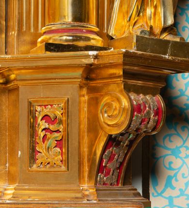 Zdjęcie nr 40: Nastawa architektoniczna, jednoosiowa, dwukondygnacyjna. Ołtarz murowany, prostopadłościenny, obity metalową blachą, zdobioną trybowaną kratownicą i gwiazdkami. Wewnątrz grób Chrystusa ze współczesną rzeźbą. Nastawa na niskim cokole, z wyodrębnionymi dwoma, ukośnie ustawionymi prostopadłościanami, z konsolami, dekorowanymi akantem i kampanulami. Pośrodku cokołu zamontowany obraz św. Faustyny w kształcie wieloboku. Kondygnacja flankowana dwiema parami pilastrów o kanelowanych trzonach oraz ustawioną przed nimi parą kolumn o kapitelach kompozytowych. Podpory dźwigają pełne belkowanie, wyłamane na ich osi, z silnie wysuniętym gzymsem, z przerwanym architrawem i fryzem nad polem środkowym. Na belkowaniu fragmenty przerwanego, wolutowego przyczółka, zwrócone pod kątem, do wewnątrz. W polu środkowym wnęka w formie stojącego prostokąta zamkniętego łukiem półkolistym, ujęta profilowaną ramą dekorowaną na bokach kwiatami, zwieńczoną muszlą. We wnęce obraz „Jezu Ufam Tobie”. Na konsolach, po bokach nastawy ustawione figury św. Kazimierza i św. Jana Kantego. Nastawa flankowana uszami utworzonymi z karbowanej wstęgi i ornamentu roślinnego. Druga kondygnacja węższa, flankowana ustawionymi pod kątem pilastrami, o trzonach dekorowanych kampanulami. Pilastry podtrzymują gzyms wyłamany na ich osi, nad polem przyjmujący kształt łuku półkolistego nadwieszonego. Na nim ustawione dwa wazony z kwiatami i bukiet kwiatów. W polu obraz św. Joachima w formie stojącego owalu, ujęty ramą, dekorowaną ornamentem roślinnym. Struktura niemal w całości złocona, elementy cokołu i fryzu polichromowane w kolorze czerwonym, ornamentyka złocona. 


