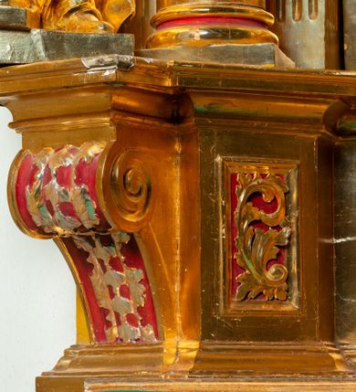 Zdjęcie nr 41: Nastawa architektoniczna, jednoosiowa, dwukondygnacyjna. Ołtarz murowany, prostopadłościenny, obity metalową blachą, zdobioną trybowaną kratownicą i gwiazdkami. Wewnątrz grób Chrystusa ze współczesną rzeźbą. Nastawa na niskim cokole, z wyodrębnionymi dwoma, ukośnie ustawionymi prostopadłościanami, z konsolami, dekorowanymi akantem i kampanulami. Pośrodku cokołu zamontowany obraz św. Faustyny w kształcie wieloboku. Kondygnacja flankowana dwiema parami pilastrów o kanelowanych trzonach oraz ustawioną przed nimi parą kolumn o kapitelach kompozytowych. Podpory dźwigają pełne belkowanie, wyłamane na ich osi, z silnie wysuniętym gzymsem, z przerwanym architrawem i fryzem nad polem środkowym. Na belkowaniu fragmenty przerwanego, wolutowego przyczółka, zwrócone pod kątem, do wewnątrz. W polu środkowym wnęka w formie stojącego prostokąta zamkniętego łukiem półkolistym, ujęta profilowaną ramą dekorowaną na bokach kwiatami, zwieńczoną muszlą. We wnęce obraz „Jezu Ufam Tobie”. Na konsolach, po bokach nastawy ustawione figury św. Kazimierza i św. Jana Kantego. Nastawa flankowana uszami utworzonymi z karbowanej wstęgi i ornamentu roślinnego. Druga kondygnacja węższa, flankowana ustawionymi pod kątem pilastrami, o trzonach dekorowanych kampanulami. Pilastry podtrzymują gzyms wyłamany na ich osi, nad polem przyjmujący kształt łuku półkolistego nadwieszonego. Na nim ustawione dwa wazony z kwiatami i bukiet kwiatów. W polu obraz św. Joachima w formie stojącego owalu, ujęty ramą, dekorowaną ornamentem roślinnym. Struktura niemal w całości złocona, elementy cokołu i fryzu polichromowane w kolorze czerwonym, ornamentyka złocona. 


