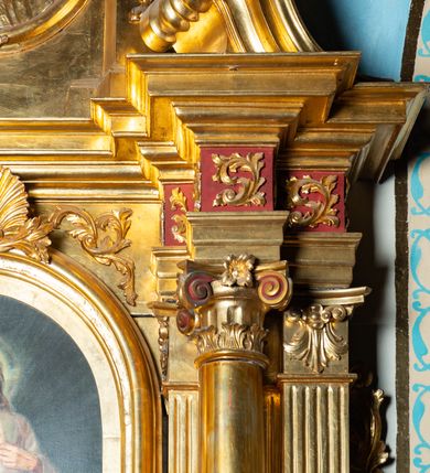 Zdjęcie nr 42: Nastawa architektoniczna, jednoosiowa, dwukondygnacyjna. Ołtarz murowany, prostopadłościenny, obity metalową blachą, zdobioną trybowaną kratownicą i gwiazdkami. Wewnątrz grób Chrystusa ze współczesną rzeźbą. Nastawa na niskim cokole, z wyodrębnionymi dwoma, ukośnie ustawionymi prostopadłościanami, z konsolami, dekorowanymi akantem i kampanulami. Pośrodku cokołu zamontowany obraz św. Faustyny w kształcie wieloboku. Kondygnacja flankowana dwiema parami pilastrów o kanelowanych trzonach oraz ustawioną przed nimi parą kolumn o kapitelach kompozytowych. Podpory dźwigają pełne belkowanie, wyłamane na ich osi, z silnie wysuniętym gzymsem, z przerwanym architrawem i fryzem nad polem środkowym. Na belkowaniu fragmenty przerwanego, wolutowego przyczółka, zwrócone pod kątem, do wewnątrz. W polu środkowym wnęka w formie stojącego prostokąta zamkniętego łukiem półkolistym, ujęta profilowaną ramą dekorowaną na bokach kwiatami, zwieńczoną muszlą. We wnęce obraz „Jezu Ufam Tobie”. Na konsolach, po bokach nastawy ustawione figury św. Kazimierza i św. Jana Kantego. Nastawa flankowana uszami utworzonymi z karbowanej wstęgi i ornamentu roślinnego. Druga kondygnacja węższa, flankowana ustawionymi pod kątem pilastrami, o trzonach dekorowanych kampanulami. Pilastry podtrzymują gzyms wyłamany na ich osi, nad polem przyjmujący kształt łuku półkolistego nadwieszonego. Na nim ustawione dwa wazony z kwiatami i bukiet kwiatów. W polu obraz św. Joachima w formie stojącego owalu, ujęty ramą, dekorowaną ornamentem roślinnym. Struktura niemal w całości złocona, elementy cokołu i fryzu polichromowane w kolorze czerwonym, ornamentyka złocona. 


