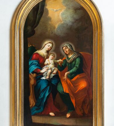 Zdjęcie nr 10: Obraz w kształcie stojącego prostokąta, zamknięty półkoliście z przedstawieniem św. Anny Samotrzeć. W centrum kompozycji ukazane zostały w pozycji siedzącej: po prawej św. Anna na czerwonym krześle, a po lewej Matka Boska z Dzieciątkiem Jezus, siedzącymi na zielonym tronie. Obie kobiety zwrócone są ku sobie. Święta Anna delikatnie pochyla się w stronę Dzieciątka i prawą ręką ujmuje je za lewą rączkę. Święta ma szczupłą twarz o starczych rysach, oczach podkreślonych cieniami i długim nosie. Ubrana jest w zieloną suknię oraz czerwony płaszcz zarzucony na plecy i kolana; na głowie ma biały welon, a wokół niej świetlisty nimb. Po lewej stronie Maria obejmuje obiema rękami Dzieciątko. Twarz pełna o bardzo jasnej karnacji, dużych oczach, długim nosie, drobnych ustach i z zaznaczonym wyraźnie podbródkiem; włosy brązowe, upięte z tyłu głowy, wokół której świetlisty nimb. Ubrana jest w czerwoną suknię oraz przerzucony przez ramiona i spływający na plecy niebieski płaszcz oraz biały welon na głowie. Dzieciątko ukazane frontalnie, półleżące z lewą nóżką delikatnie uniesioną, lewą ręką ujmuje dłoń św. Anny, a w prawej trzyma krzyż. Twarz owalna o delikatnych rysach, włosy krótkie i kędzierzawe, wokół głowy ma świetlisty nimb. Przewiązany jest w biodrach białą tkaniną. W górnej części kompozycji znajduje się gołębica Ducha Świętego z rozpostartymi szeroko skrzydłami na tle złotego nieba. W tle obrazu skłębione, ciemne obłoki. Po lewej stronie kompozycji fragment ciemnej, podwieszonej kotary. Kolorystyka ciemnobrunatna o intensywnych kolorach szat. Rama drewniana, profilowana, złocona.