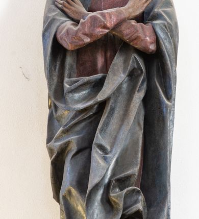Zdjęcie nr 3: Rzeźba pełna, ustawiona na niewielkiej, owalnej podstawie. Maria przedstawiona frontalnie, w pozycji stojącej z rękami skrzyżowanymi na wysokości piersi. Matka Chrystusa została przedstawiona jako szczupła kobieta o owalnej twarzy o zasmuconym wyrazie. Wyraźnie zaznaczone łuki brwiowe, długi prosty nos i niewielkie usta. Oczy skierowane przed siebie. Dłonie o długich i szczupłych palcach. Maria ubrana jest w fioletową suknię z długimi rękawami oraz obszerny, ciemnogranatowy płaszcz szczelnie otulający ciało i tworzący głęboko łamane, ostre fałdy. Na głowie Marii biała chusta oraz podwika. Figura w pełni polichromowana.