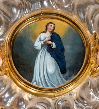 Zdjęcie nr 23: Ołtarz architektoniczny, jednokondygnacyjny, jednoosiowy ze zwieńczeniem i drewnianą, sarkofagową mensą. Na mensie ołtarza kremowe tabernakulum w formie prostopadłościennej szafki, ujęte parą jońskich, złoconych półkolumienek, stojących na profilowanym  cokoliku, wspierających belkowanie przechodzące nad polem centralnym w łuk. Drzwiczki w kształcie stojącego prostokąta zamkniętego łukiem pełnym zdobione płaskorzeźbionym motywem kielicha z hostią w glorii. Retabulum ołtarzowe na cokole, ujęte parą kolumn kompozytowych o spiralnie skręconych trzonach.  Podpory wspierają wyłamujące się ponad nimi oraz między nimi belkowanie o wysuniętym gzymsie, podtrzymujące przerwane fragmenty przyczółka. Pole środkowe w formie wnęki w kształcie stojącego prostokąta zamkniętego łukiem nadwieszonym z obrazem św. Anny Samotrzeć. Ujmuje ją para figur ustawionych na wysokich, zdwojonych cokołach. Postać z lewej strony trzyma berło, postać z prawej jabłko królewskie.  Zwieńczenie w formie stojącego owalu ujętego skłębionymi obłokami i szeroką glorią promienistą. W polu przedstawienie Matki Boskiej ujęte główkami anielskimi i parą putt. 
 Pola cokołu dekorowane płycinami. Na trzonach kolumn retabulum spiralnie oplatająca je wić roślinna. Wewnętrzne fragmenty wyłamanego gzymsu podtrzymują konsole, pod którymi podwieszono bukiety kwiatów. Struktura ołtarza polichromowana z imitacją marmoryzacji w odcieniach białym i kremowym, tło głowic kolumn czerwone, dekoracje i profile złocone i srebrzone. 
