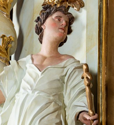 Zdjęcie nr 8: Ołtarz architektoniczny, jednokondygnacyjny, jednoosiowy ze zwieńczeniem i drewnianą, sarkofagową mensą. Na mensie ołtarza kremowe tabernakulum w formie prostopadłościennej szafki, ujęte parą jońskich, złoconych półkolumienek, stojących na profilowanym  cokoliku, wspierających belkowanie przechodzące nad polem centralnym w łuk. Drzwiczki w kształcie stojącego prostokąta zamkniętego łukiem pełnym zdobione płaskorzeźbionym motywem kielicha z hostią w glorii. Retabulum ołtarzowe na cokole, ujęte parą kolumn kompozytowych o spiralnie skręconych trzonach.  Podpory wspierają wyłamujące się ponad nimi oraz między nimi belkowanie o wysuniętym gzymsie, podtrzymujące przerwane fragmenty przyczółka. Pole środkowe w formie wnęki w kształcie stojącego prostokąta zamkniętego łukiem nadwieszonym z obrazem św. Anny Samotrzeć. Ujmuje ją para figur ustawionych na wysokich, zdwojonych cokołach. Postać z lewej strony trzyma berło, postać z prawej jabłko królewskie.  Zwieńczenie w formie stojącego owalu ujętego skłębionymi obłokami i szeroką glorią promienistą. W polu przedstawienie Matki Boskiej ujęte główkami anielskimi i parą putt. 
 Pola cokołu dekorowane płycinami. Na trzonach kolumn retabulum spiralnie oplatająca je wić roślinna. Wewnętrzne fragmenty wyłamanego gzymsu podtrzymują konsole, pod którymi podwieszono bukiety kwiatów. Struktura ołtarza polichromowana z imitacją marmoryzacji w odcieniach białym i kremowym, tło głowic kolumn czerwone, dekoracje i profile złocone i srebrzone. 
