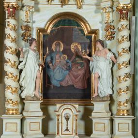 Zdjęcie nr 1: Ołtarz architektoniczny, jednokondygnacyjny, jednoosiowy ze zwieńczeniem i drewnianą, sarkofagową mensą. Na mensie ołtarza kremowe tabernakulum w formie prostopadłościennej szafki, ujęte parą jońskich, złoconych półkolumienek, stojących na profilowanym  cokoliku, wspierających belkowanie przechodzące nad polem centralnym w łuk. Drzwiczki w kształcie stojącego prostokąta zamkniętego łukiem pełnym zdobione płaskorzeźbionym motywem kielicha z hostią w glorii. Retabulum ołtarzowe na cokole, ujęte parą kolumn kompozytowych o spiralnie skręconych trzonach.  Podpory wspierają wyłamujące się ponad nimi oraz między nimi belkowanie o wysuniętym gzymsie, podtrzymujące przerwane fragmenty przyczółka. Pole środkowe w formie wnęki w kształcie stojącego prostokąta zamkniętego łukiem nadwieszonym z obrazem św. Anny Samotrzeć. Ujmuje ją para figur ustawionych na wysokich, zdwojonych cokołach. Postać z lewej strony trzyma berło, postać z prawej jabłko królewskie.  Zwieńczenie w formie stojącego owalu ujętego skłębionymi obłokami i szeroką glorią promienistą. W polu przedstawienie Matki Boskiej ujęte główkami anielskimi i parą putt. 
 Pola cokołu dekorowane płycinami. Na trzonach kolumn retabulum spiralnie oplatająca je wić roślinna. Wewnętrzne fragmenty wyłamanego gzymsu podtrzymują konsole, pod którymi podwieszono bukiety kwiatów. Struktura ołtarza polichromowana z imitacją marmoryzacji w odcieniach białym i kremowym, tło głowic kolumn czerwone, dekoracje i profile złocone i srebrzone. 
