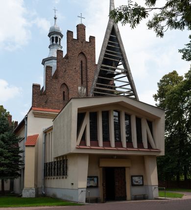 Zdjęcie nr 1: Kościół orientowany, murowany z cegły i kamienia, jednonawowy z trójprzęsłowym prezbiterium zamkniętym wielobocznie, sklepionym krzyżowo-żebrowo. Od północy umieszczona prostokątna, piętrowa zakrystia sklepiona kolebkowo (pięterko nad zakrystią dodane w 1885), dostępna kamiennym portalem o wykroju prostokątnym od strony wschodniej. Ściana północna zakrystii zakończona schodkowo z dekoracją blendową. Również od północy, na szerokości nawy do kościoła przylega prostokątna kaplica nakryta dachem czterospadowym zwieńczonym czworoboczną wieżyczką dostępna od zachodu przez prostokątną kruchtę z portalem o wykroju prostokątnym ujętym dwulalkowymi, kamiennymi balaskami. Kruchta zwieńczona trójkątnym przyczółkiem, na którym kamienny krzyż. Trójprzęsłowa nawa wyższa i szersza od prezbiterium i przesunięta w stosunku do jego osi ku stronie północnej, nakryta stropem. Północny mur nawy w części zachodniej poszerzony do pewnej wysokości dla pomieszczenia w jego grubości schodów prowadzących na chór muzyczny. Okna prostokątne zamknięte łukiem półkolistym. Zachodni i wschodni szczyt nawy zamknięty schodkowo. Od strony wschodniej trzy ostrołukowe blendy, w środkowej, wyżej od bocznych umieszczona tarcza herbowa z wizerunkiem św. Stanisława oraz Orła Białego. Od południa do nawy przylega prostokątna kruchta z kamiennym, ostrołukowym portalem nakryta dachem pulpitowym. Od strony zachodniej do bryły kościoła dostawiona prostokątna, współczesna kruchta wraz z chórem muzycznym (dobudowana w 1966) dostępna portalem o wykroju prostokątnym, nakryta dwuspadowym dachem. W ścianach bocznych wąskie, smukłe okna w kształcie stojącego prostokąta. Ponad kruchtą ażurowa dzwonnica na rzucie trójkąta zwieńczona krzyżem. Wieżyczka na sygnaturkę na rzucie ośmioboku zwieńczona barokowym hełmem z glorietą i krzyżem. Od zewnątrz kościół częściowo tynkowany, nawa i prezbiterium opięte szkarpami. Dachy kryte dachówką oraz blachą (część wschodnia prezbiterium).