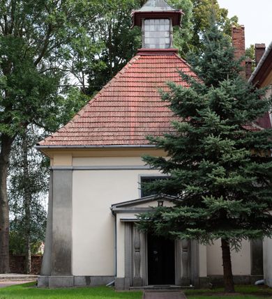 Zdjęcie nr 54: Kościół orientowany, murowany z cegły i kamienia, jednonawowy z trójprzęsłowym prezbiterium zamkniętym wielobocznie, sklepionym krzyżowo-żebrowo. Od północy umieszczona prostokątna, piętrowa zakrystia sklepiona kolebkowo (pięterko nad zakrystią dodane w 1885), dostępna kamiennym portalem o wykroju prostokątnym od strony wschodniej. Ściana północna zakrystii zakończona schodkowo z dekoracją blendową. Również od północy, na szerokości nawy do kościoła przylega prostokątna kaplica nakryta dachem czterospadowym zwieńczonym czworoboczną wieżyczką dostępna od zachodu przez prostokątną kruchtę z portalem o wykroju prostokątnym ujętym dwulalkowymi, kamiennymi balaskami. Kruchta zwieńczona trójkątnym przyczółkiem, na którym kamienny krzyż. Trójprzęsłowa nawa wyższa i szersza od prezbiterium i przesunięta w stosunku do jego osi ku stronie północnej, nakryta stropem. Północny mur nawy w części zachodniej poszerzony do pewnej wysokości dla pomieszczenia w jego grubości schodów prowadzących na chór muzyczny. Okna prostokątne zamknięte łukiem półkolistym. Zachodni i wschodni szczyt nawy zamknięty schodkowo. Od strony wschodniej trzy ostrołukowe blendy, w środkowej, wyżej od bocznych umieszczona tarcza herbowa z wizerunkiem św. Stanisława oraz Orła Białego. Od południa do nawy przylega prostokątna kruchta z kamiennym, ostrołukowym portalem nakryta dachem pulpitowym. Od strony zachodniej do bryły kościoła dostawiona prostokątna, współczesna kruchta wraz z chórem muzycznym (dobudowana w 1966) dostępna portalem o wykroju prostokątnym, nakryta dwuspadowym dachem. W ścianach bocznych wąskie, smukłe okna w kształcie stojącego prostokąta. Ponad kruchtą ażurowa dzwonnica na rzucie trójkąta zwieńczona krzyżem. Wieżyczka na sygnaturkę na rzucie ośmioboku zwieńczona barokowym hełmem z glorietą i krzyżem. Od zewnątrz kościół częściowo tynkowany, nawa i prezbiterium opięte szkarpami. Dachy kryte dachówką oraz blachą (część wschodnia prezbiterium).