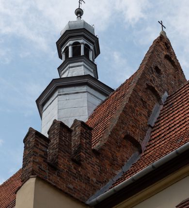 Zdjęcie nr 19: Kościół orientowany, murowany z cegły i kamienia, jednonawowy z trójprzęsłowym prezbiterium zamkniętym wielobocznie, sklepionym krzyżowo-żebrowo. Od północy umieszczona prostokątna, piętrowa zakrystia sklepiona kolebkowo (pięterko nad zakrystią dodane w 1885), dostępna kamiennym portalem o wykroju prostokątnym od strony wschodniej. Ściana północna zakrystii zakończona schodkowo z dekoracją blendową. Również od północy, na szerokości nawy do kościoła przylega prostokątna kaplica nakryta dachem czterospadowym zwieńczonym czworoboczną wieżyczką dostępna od zachodu przez prostokątną kruchtę z portalem o wykroju prostokątnym ujętym dwulalkowymi, kamiennymi balaskami. Kruchta zwieńczona trójkątnym przyczółkiem, na którym kamienny krzyż. Trójprzęsłowa nawa wyższa i szersza od prezbiterium i przesunięta w stosunku do jego osi ku stronie północnej, nakryta stropem. Północny mur nawy w części zachodniej poszerzony do pewnej wysokości dla pomieszczenia w jego grubości schodów prowadzących na chór muzyczny. Okna prostokątne zamknięte łukiem półkolistym. Zachodni i wschodni szczyt nawy zamknięty schodkowo. Od strony wschodniej trzy ostrołukowe blendy, w środkowej, wyżej od bocznych umieszczona tarcza herbowa z wizerunkiem św. Stanisława oraz Orła Białego. Od południa do nawy przylega prostokątna kruchta z kamiennym, ostrołukowym portalem nakryta dachem pulpitowym. Od strony zachodniej do bryły kościoła dostawiona prostokątna, współczesna kruchta wraz z chórem muzycznym (dobudowana w 1966) dostępna portalem o wykroju prostokątnym, nakryta dwuspadowym dachem. W ścianach bocznych wąskie, smukłe okna w kształcie stojącego prostokąta. Ponad kruchtą ażurowa dzwonnica na rzucie trójkąta zwieńczona krzyżem. Wieżyczka na sygnaturkę na rzucie ośmioboku zwieńczona barokowym hełmem z glorietą i krzyżem. Od zewnątrz kościół częściowo tynkowany, nawa i prezbiterium opięte szkarpami. Dachy kryte dachówką oraz blachą (część wschodnia prezbiterium).