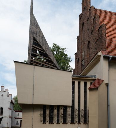 Zdjęcie nr 43: Kościół orientowany, murowany z cegły i kamienia, jednonawowy z trójprzęsłowym prezbiterium zamkniętym wielobocznie, sklepionym krzyżowo-żebrowo. Od północy umieszczona prostokątna, piętrowa zakrystia sklepiona kolebkowo (pięterko nad zakrystią dodane w 1885), dostępna kamiennym portalem o wykroju prostokątnym od strony wschodniej. Ściana północna zakrystii zakończona schodkowo z dekoracją blendową. Również od północy, na szerokości nawy do kościoła przylega prostokątna kaplica nakryta dachem czterospadowym zwieńczonym czworoboczną wieżyczką dostępna od zachodu przez prostokątną kruchtę z portalem o wykroju prostokątnym ujętym dwulalkowymi, kamiennymi balaskami. Kruchta zwieńczona trójkątnym przyczółkiem, na którym kamienny krzyż. Trójprzęsłowa nawa wyższa i szersza od prezbiterium i przesunięta w stosunku do jego osi ku stronie północnej, nakryta stropem. Północny mur nawy w części zachodniej poszerzony do pewnej wysokości dla pomieszczenia w jego grubości schodów prowadzących na chór muzyczny. Okna prostokątne zamknięte łukiem półkolistym. Zachodni i wschodni szczyt nawy zamknięty schodkowo. Od strony wschodniej trzy ostrołukowe blendy, w środkowej, wyżej od bocznych umieszczona tarcza herbowa z wizerunkiem św. Stanisława oraz Orła Białego. Od południa do nawy przylega prostokątna kruchta z kamiennym, ostrołukowym portalem nakryta dachem pulpitowym. Od strony zachodniej do bryły kościoła dostawiona prostokątna, współczesna kruchta wraz z chórem muzycznym (dobudowana w 1966) dostępna portalem o wykroju prostokątnym, nakryta dwuspadowym dachem. W ścianach bocznych wąskie, smukłe okna w kształcie stojącego prostokąta. Ponad kruchtą ażurowa dzwonnica na rzucie trójkąta zwieńczona krzyżem. Wieżyczka na sygnaturkę na rzucie ośmioboku zwieńczona barokowym hełmem z glorietą i krzyżem. Od zewnątrz kościół częściowo tynkowany, nawa i prezbiterium opięte szkarpami. Dachy kryte dachówką oraz blachą (część wschodnia prezbiterium).