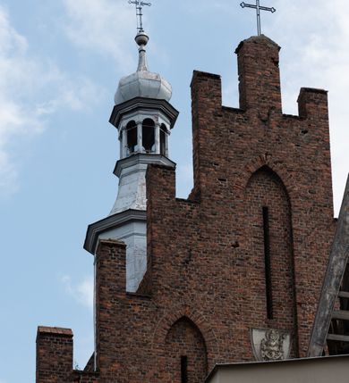 Zdjęcie nr 25: Kościół orientowany, murowany z cegły i kamienia, jednonawowy z trójprzęsłowym prezbiterium zamkniętym wielobocznie, sklepionym krzyżowo-żebrowo. Od północy umieszczona prostokątna, piętrowa zakrystia sklepiona kolebkowo (pięterko nad zakrystią dodane w 1885), dostępna kamiennym portalem o wykroju prostokątnym od strony wschodniej. Ściana północna zakrystii zakończona schodkowo z dekoracją blendową. Również od północy, na szerokości nawy do kościoła przylega prostokątna kaplica nakryta dachem czterospadowym zwieńczonym czworoboczną wieżyczką dostępna od zachodu przez prostokątną kruchtę z portalem o wykroju prostokątnym ujętym dwulalkowymi, kamiennymi balaskami. Kruchta zwieńczona trójkątnym przyczółkiem, na którym kamienny krzyż. Trójprzęsłowa nawa wyższa i szersza od prezbiterium i przesunięta w stosunku do jego osi ku stronie północnej, nakryta stropem. Północny mur nawy w części zachodniej poszerzony do pewnej wysokości dla pomieszczenia w jego grubości schodów prowadzących na chór muzyczny. Okna prostokątne zamknięte łukiem półkolistym. Zachodni i wschodni szczyt nawy zamknięty schodkowo. Od strony wschodniej trzy ostrołukowe blendy, w środkowej, wyżej od bocznych umieszczona tarcza herbowa z wizerunkiem św. Stanisława oraz Orła Białego. Od południa do nawy przylega prostokątna kruchta z kamiennym, ostrołukowym portalem nakryta dachem pulpitowym. Od strony zachodniej do bryły kościoła dostawiona prostokątna, współczesna kruchta wraz z chórem muzycznym (dobudowana w 1966) dostępna portalem o wykroju prostokątnym, nakryta dwuspadowym dachem. W ścianach bocznych wąskie, smukłe okna w kształcie stojącego prostokąta. Ponad kruchtą ażurowa dzwonnica na rzucie trójkąta zwieńczona krzyżem. Wieżyczka na sygnaturkę na rzucie ośmioboku zwieńczona barokowym hełmem z glorietą i krzyżem. Od zewnątrz kościół częściowo tynkowany, nawa i prezbiterium opięte szkarpami. Dachy kryte dachówką oraz blachą (część wschodnia prezbiterium).