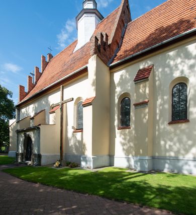 Zdjęcie nr 26: Kościół orientowany, murowany z cegły i kamienia, jednonawowy z trójprzęsłowym prezbiterium zamkniętym wielobocznie, sklepionym krzyżowo-żebrowo. Od północy umieszczona prostokątna, piętrowa zakrystia sklepiona kolebkowo (pięterko nad zakrystią dodane w 1885), dostępna kamiennym portalem o wykroju prostokątnym od strony wschodniej. Ściana północna zakrystii zakończona schodkowo z dekoracją blendową. Również od północy, na szerokości nawy do kościoła przylega prostokątna kaplica nakryta dachem czterospadowym zwieńczonym czworoboczną wieżyczką dostępna od zachodu przez prostokątną kruchtę z portalem o wykroju prostokątnym ujętym dwulalkowymi, kamiennymi balaskami. Kruchta zwieńczona trójkątnym przyczółkiem, na którym kamienny krzyż. Trójprzęsłowa nawa wyższa i szersza od prezbiterium i przesunięta w stosunku do jego osi ku stronie północnej, nakryta stropem. Północny mur nawy w części zachodniej poszerzony do pewnej wysokości dla pomieszczenia w jego grubości schodów prowadzących na chór muzyczny. Okna prostokątne zamknięte łukiem półkolistym. Zachodni i wschodni szczyt nawy zamknięty schodkowo. Od strony wschodniej trzy ostrołukowe blendy, w środkowej, wyżej od bocznych umieszczona tarcza herbowa z wizerunkiem św. Stanisława oraz Orła Białego. Od południa do nawy przylega prostokątna kruchta z kamiennym, ostrołukowym portalem nakryta dachem pulpitowym. Od strony zachodniej do bryły kościoła dostawiona prostokątna, współczesna kruchta wraz z chórem muzycznym (dobudowana w 1966) dostępna portalem o wykroju prostokątnym, nakryta dwuspadowym dachem. W ścianach bocznych wąskie, smukłe okna w kształcie stojącego prostokąta. Ponad kruchtą ażurowa dzwonnica na rzucie trójkąta zwieńczona krzyżem. Wieżyczka na sygnaturkę na rzucie ośmioboku zwieńczona barokowym hełmem z glorietą i krzyżem. Od zewnątrz kościół częściowo tynkowany, nawa i prezbiterium opięte szkarpami. Dachy kryte dachówką oraz blachą (część wschodnia prezbiterium).