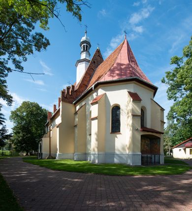 Zdjęcie nr 27: Kościół orientowany, murowany z cegły i kamienia, jednonawowy z trójprzęsłowym prezbiterium zamkniętym wielobocznie, sklepionym krzyżowo-żebrowo. Od północy umieszczona prostokątna, piętrowa zakrystia sklepiona kolebkowo (pięterko nad zakrystią dodane w 1885), dostępna kamiennym portalem o wykroju prostokątnym od strony wschodniej. Ściana północna zakrystii zakończona schodkowo z dekoracją blendową. Również od północy, na szerokości nawy do kościoła przylega prostokątna kaplica nakryta dachem czterospadowym zwieńczonym czworoboczną wieżyczką dostępna od zachodu przez prostokątną kruchtę z portalem o wykroju prostokątnym ujętym dwulalkowymi, kamiennymi balaskami. Kruchta zwieńczona trójkątnym przyczółkiem, na którym kamienny krzyż. Trójprzęsłowa nawa wyższa i szersza od prezbiterium i przesunięta w stosunku do jego osi ku stronie północnej, nakryta stropem. Północny mur nawy w części zachodniej poszerzony do pewnej wysokości dla pomieszczenia w jego grubości schodów prowadzących na chór muzyczny. Okna prostokątne zamknięte łukiem półkolistym. Zachodni i wschodni szczyt nawy zamknięty schodkowo. Od strony wschodniej trzy ostrołukowe blendy, w środkowej, wyżej od bocznych umieszczona tarcza herbowa z wizerunkiem św. Stanisława oraz Orła Białego. Od południa do nawy przylega prostokątna kruchta z kamiennym, ostrołukowym portalem nakryta dachem pulpitowym. Od strony zachodniej do bryły kościoła dostawiona prostokątna, współczesna kruchta wraz z chórem muzycznym (dobudowana w 1966) dostępna portalem o wykroju prostokątnym, nakryta dwuspadowym dachem. W ścianach bocznych wąskie, smukłe okna w kształcie stojącego prostokąta. Ponad kruchtą ażurowa dzwonnica na rzucie trójkąta zwieńczona krzyżem. Wieżyczka na sygnaturkę na rzucie ośmioboku zwieńczona barokowym hełmem z glorietą i krzyżem. Od zewnątrz kościół częściowo tynkowany, nawa i prezbiterium opięte szkarpami. Dachy kryte dachówką oraz blachą (część wschodnia prezbiterium).