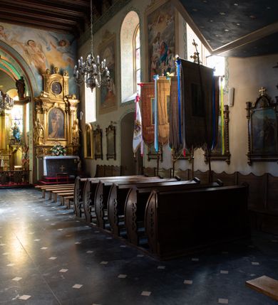 Zdjęcie nr 37: Kościół orientowany, murowany z cegły i kamienia, jednonawowy z trójprzęsłowym prezbiterium zamkniętym wielobocznie, sklepionym krzyżowo-żebrowo. Od północy umieszczona prostokątna, piętrowa zakrystia sklepiona kolebkowo (pięterko nad zakrystią dodane w 1885), dostępna kamiennym portalem o wykroju prostokątnym od strony wschodniej. Ściana północna zakrystii zakończona schodkowo z dekoracją blendową. Również od północy, na szerokości nawy do kościoła przylega prostokątna kaplica nakryta dachem czterospadowym zwieńczonym czworoboczną wieżyczką dostępna od zachodu przez prostokątną kruchtę z portalem o wykroju prostokątnym ujętym dwulalkowymi, kamiennymi balaskami. Kruchta zwieńczona trójkątnym przyczółkiem, na którym kamienny krzyż. Trójprzęsłowa nawa wyższa i szersza od prezbiterium i przesunięta w stosunku do jego osi ku stronie północnej, nakryta stropem. Północny mur nawy w części zachodniej poszerzony do pewnej wysokości dla pomieszczenia w jego grubości schodów prowadzących na chór muzyczny. Okna prostokątne zamknięte łukiem półkolistym. Zachodni i wschodni szczyt nawy zamknięty schodkowo. Od strony wschodniej trzy ostrołukowe blendy, w środkowej, wyżej od bocznych umieszczona tarcza herbowa z wizerunkiem św. Stanisława oraz Orła Białego. Od południa do nawy przylega prostokątna kruchta z kamiennym, ostrołukowym portalem nakryta dachem pulpitowym. Od strony zachodniej do bryły kościoła dostawiona prostokątna, współczesna kruchta wraz z chórem muzycznym (dobudowana w 1966) dostępna portalem o wykroju prostokątnym, nakryta dwuspadowym dachem. W ścianach bocznych wąskie, smukłe okna w kształcie stojącego prostokąta. Ponad kruchtą ażurowa dzwonnica na rzucie trójkąta zwieńczona krzyżem. Wieżyczka na sygnaturkę na rzucie ośmioboku zwieńczona barokowym hełmem z glorietą i krzyżem. Od zewnątrz kościół częściowo tynkowany, nawa i prezbiterium opięte szkarpami. Dachy kryte dachówką oraz blachą (część wschodnia prezbiterium).