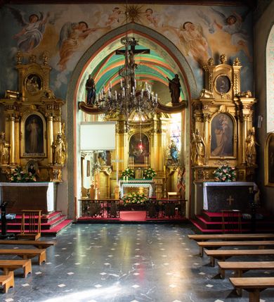 Zdjęcie nr 39: Kościół orientowany, murowany z cegły i kamienia, jednonawowy z trójprzęsłowym prezbiterium zamkniętym wielobocznie, sklepionym krzyżowo-żebrowo. Od północy umieszczona prostokątna, piętrowa zakrystia sklepiona kolebkowo (pięterko nad zakrystią dodane w 1885), dostępna kamiennym portalem o wykroju prostokątnym od strony wschodniej. Ściana północna zakrystii zakończona schodkowo z dekoracją blendową. Również od północy, na szerokości nawy do kościoła przylega prostokątna kaplica nakryta dachem czterospadowym zwieńczonym czworoboczną wieżyczką dostępna od zachodu przez prostokątną kruchtę z portalem o wykroju prostokątnym ujętym dwulalkowymi, kamiennymi balaskami. Kruchta zwieńczona trójkątnym przyczółkiem, na którym kamienny krzyż. Trójprzęsłowa nawa wyższa i szersza od prezbiterium i przesunięta w stosunku do jego osi ku stronie północnej, nakryta stropem. Północny mur nawy w części zachodniej poszerzony do pewnej wysokości dla pomieszczenia w jego grubości schodów prowadzących na chór muzyczny. Okna prostokątne zamknięte łukiem półkolistym. Zachodni i wschodni szczyt nawy zamknięty schodkowo. Od strony wschodniej trzy ostrołukowe blendy, w środkowej, wyżej od bocznych umieszczona tarcza herbowa z wizerunkiem św. Stanisława oraz Orła Białego. Od południa do nawy przylega prostokątna kruchta z kamiennym, ostrołukowym portalem nakryta dachem pulpitowym. Od strony zachodniej do bryły kościoła dostawiona prostokątna, współczesna kruchta wraz z chórem muzycznym (dobudowana w 1966) dostępna portalem o wykroju prostokątnym, nakryta dwuspadowym dachem. W ścianach bocznych wąskie, smukłe okna w kształcie stojącego prostokąta. Ponad kruchtą ażurowa dzwonnica na rzucie trójkąta zwieńczona krzyżem. Wieżyczka na sygnaturkę na rzucie ośmioboku zwieńczona barokowym hełmem z glorietą i krzyżem. Od zewnątrz kościół częściowo tynkowany, nawa i prezbiterium opięte szkarpami. Dachy kryte dachówką oraz blachą (część wschodnia prezbiterium).