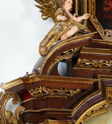 Zdjęcie nr 11: Ołtarz architektoniczny, dwukondygnacyjny, jednoosiowy ze zwieńczeniem. Mensa prostopadłościenna, antepedium w kształcie leżącego prostokąta, flankowane dwoma kanelowanymi pilastrami. W polu płycina w kształcie leżącego prostokąta wypełniona symetryczną dekoracją z akantu na czerwonym tle z sercem przebitym mieczem pośrodku. Cokół nastawy ustawiony na jednym stopniu, pośrodku zdobiony płyciną w kształcie leżącego prostokąta o zaokrąglonych krótszych bokach, cokoły pod kolumnami dekorowane mniejszymi płycinami wypełnionymi dekoracją roślinną. Pierwsza kondygnacja ujęta parą kolumn dźwigających przerwane belkowanie z przyczółkami, po bokach dodatkowo flankowana uszami wykończonymi ornamentem małżowinowo-chrząstkowym. W polu głównym obraz Najświętsze Serce Jezusa. Po bokach nastawy dwie rzeźby: po prawej św. Kazimierz Królewicz, a po lewej św. Alojzy Gonzaga. Na przyczółkach usadzone dwie rzeźby aniołów z rozłożonymi szeroko rękami. Kolumny ustawione na tle prostokątnych płycin, z bazami, trzony gładkie, kapitele kompozytowe. Druga kondygnacja flankowana parą kolumn podtrzymujących wyłamane belkowanie. W polu, w ramie o kształcie stojącego prostokąta o ściętych narożach obraz św. Michała Archanioła. W zwieńczeniu promienista gloria z monogramem Chrystusa na czerwonym tle, obwiedzionym wieńcem z obłoków. Zwieńczenie ujęte po bokach uszami. Struktura malowana w kolorze naturalnego drewna, ornamentyka złocona, detale srebrzone i czerwone.
