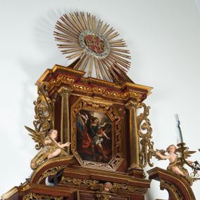 Zdjęcie nr 1: Ołtarz architektoniczny, dwukondygnacyjny, jednoosiowy ze zwieńczeniem. Mensa prostopadłościenna, antepedium w kształcie leżącego prostokąta, flankowane dwoma kanelowanymi pilastrami. W polu płycina w kształcie leżącego prostokąta wypełniona symetryczną dekoracją z akantu na czerwonym tle z sercem przebitym mieczem pośrodku. Cokół nastawy ustawiony na jednym stopniu, pośrodku zdobiony płyciną w kształcie leżącego prostokąta o zaokrąglonych krótszych bokach, cokoły pod kolumnami dekorowane mniejszymi płycinami wypełnionymi dekoracją roślinną. Pierwsza kondygnacja ujęta parą kolumn dźwigających przerwane belkowanie z przyczółkami, po bokach dodatkowo flankowana uszami wykończonymi ornamentem małżowinowo-chrząstkowym. W polu głównym obraz Najświętsze Serce Jezusa. Po bokach nastawy dwie rzeźby: po prawej św. Kazimierz Królewicz, a po lewej św. Alojzy Gonzaga. Na przyczółkach usadzone dwie rzeźby aniołów z rozłożonymi szeroko rękami. Kolumny ustawione na tle prostokątnych płycin, z bazami, trzony gładkie, kapitele kompozytowe. Druga kondygnacja flankowana parą kolumn podtrzymujących wyłamane belkowanie. W polu, w ramie o kształcie stojącego prostokąta o ściętych narożach obraz św. Michała Archanioła. W zwieńczeniu promienista gloria z monogramem Chrystusa na czerwonym tle, obwiedzionym wieńcem z obłoków. Zwieńczenie ujęte po bokach uszami. Struktura malowana w kolorze naturalnego drewna, ornamentyka złocona, detale srebrzone i czerwone.
