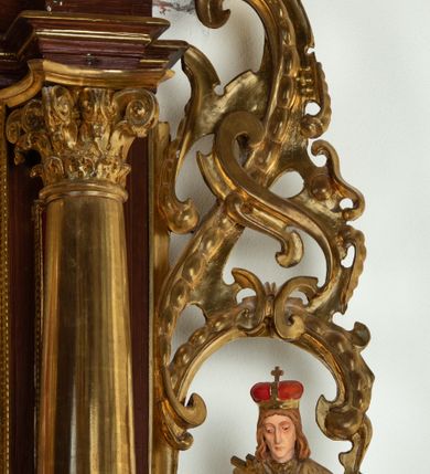 Zdjęcie nr 20: Ołtarz architektoniczny, dwukondygnacyjny, jednoosiowy ze zwieńczeniem. Mensa prostopadłościenna, antepedium w kształcie leżącego prostokąta, flankowane dwoma kanelowanymi pilastrami. W polu płycina w kształcie leżącego prostokąta wypełniona symetryczną dekoracją z akantu na czerwonym tle z sercem przebitym mieczem pośrodku. Cokół nastawy ustawiony na jednym stopniu, pośrodku zdobiony płyciną w kształcie leżącego prostokąta o zaokrąglonych krótszych bokach, cokoły pod kolumnami dekorowane mniejszymi płycinami wypełnionymi dekoracją roślinną. Pierwsza kondygnacja ujęta parą kolumn dźwigających przerwane belkowanie z przyczółkami, po bokach dodatkowo flankowana uszami wykończonymi ornamentem małżowinowo-chrząstkowym. W polu głównym obraz Najświętsze Serce Jezusa. Po bokach nastawy dwie rzeźby: po prawej św. Kazimierz Królewicz, a po lewej św. Alojzy Gonzaga. Na przyczółkach usadzone dwie rzeźby aniołów z rozłożonymi szeroko rękami. Kolumny ustawione na tle prostokątnych płycin, z bazami, trzony gładkie, kapitele kompozytowe. Druga kondygnacja flankowana parą kolumn podtrzymujących wyłamane belkowanie. W polu, w ramie o kształcie stojącego prostokąta o ściętych narożach obraz św. Michała Archanioła. W zwieńczeniu promienista gloria z monogramem Chrystusa na czerwonym tle, obwiedzionym wieńcem z obłoków. Zwieńczenie ujęte po bokach uszami. Struktura malowana w kolorze naturalnego drewna, ornamentyka złocona, detale srebrzone i czerwone.
