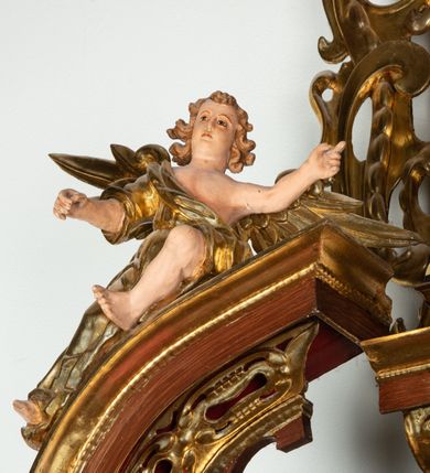 Zdjęcie nr 12: Ołtarz architektoniczny, dwukondygnacyjny, jednoosiowy ze zwieńczeniem. Mensa prostopadłościenna, antepedium w kształcie leżącego prostokąta, flankowane dwoma kanelowanymi pilastrami. W polu płycina w kształcie leżącego prostokąta wypełniona symetryczną dekoracją z akantu na czerwonym tle z sercem przebitym mieczem pośrodku. Cokół nastawy ustawiony na jednym stopniu, pośrodku zdobiony płyciną w kształcie leżącego prostokąta o zaokrąglonych krótszych bokach, cokoły pod kolumnami dekorowane mniejszymi płycinami wypełnionymi dekoracją roślinną. Pierwsza kondygnacja ujęta parą kolumn dźwigających przerwane belkowanie z przyczółkami, po bokach dodatkowo flankowana uszami wykończonymi ornamentem małżowinowo-chrząstkowym. W polu głównym obraz Najświętsze Serce Jezusa. Po bokach nastawy dwie rzeźby: po prawej św. Kazimierz Królewicz, a po lewej św. Alojzy Gonzaga. Na przyczółkach usadzone dwie rzeźby aniołów z rozłożonymi szeroko rękami. Kolumny ustawione na tle prostokątnych płycin, z bazami, trzony gładkie, kapitele kompozytowe. Druga kondygnacja flankowana parą kolumn podtrzymujących wyłamane belkowanie. W polu, w ramie o kształcie stojącego prostokąta o ściętych narożach obraz św. Michała Archanioła. W zwieńczeniu promienista gloria z monogramem Chrystusa na czerwonym tle, obwiedzionym wieńcem z obłoków. Zwieńczenie ujęte po bokach uszami. Struktura malowana w kolorze naturalnego drewna, ornamentyka złocona, detale srebrzone i czerwone.
