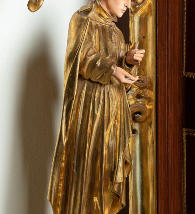 Zdjęcie nr 24: Ołtarz architektoniczny, dwukondygnacyjny, jednoosiowy ze zwieńczeniem. Mensa prostopadłościenna, antepedium w kształcie leżącego prostokąta, flankowane dwoma kanelowanymi pilastrami. W polu płycina w kształcie leżącego prostokąta wypełniona symetryczną dekoracją z akantu na czerwonym tle z sercem przebitym mieczem pośrodku. Cokół nastawy ustawiony na jednym stopniu, pośrodku zdobiony płyciną w kształcie leżącego prostokąta o zaokrąglonych krótszych bokach, cokoły pod kolumnami dekorowane mniejszymi płycinami wypełnionymi dekoracją roślinną. Pierwsza kondygnacja ujęta parą kolumn dźwigających przerwane belkowanie z przyczółkami, po bokach dodatkowo flankowana uszami wykończonymi ornamentem małżowinowo-chrząstkowym. W polu głównym obraz Najświętsze Serce Jezusa. Po bokach nastawy dwie rzeźby: po prawej św. Kazimierz Królewicz, a po lewej św. Alojzy Gonzaga. Na przyczółkach usadzone dwie rzeźby aniołów z rozłożonymi szeroko rękami. Kolumny ustawione na tle prostokątnych płycin, z bazami, trzony gładkie, kapitele kompozytowe. Druga kondygnacja flankowana parą kolumn podtrzymujących wyłamane belkowanie. W polu, w ramie o kształcie stojącego prostokąta o ściętych narożach obraz św. Michała Archanioła. W zwieńczeniu promienista gloria z monogramem Chrystusa na czerwonym tle, obwiedzionym wieńcem z obłoków. Zwieńczenie ujęte po bokach uszami. Struktura malowana w kolorze naturalnego drewna, ornamentyka złocona, detale srebrzone i czerwone.
