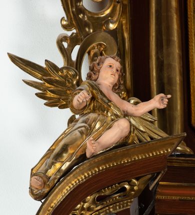 Zdjęcie nr 10: Ołtarz architektoniczny, dwukondygnacyjny, jednoosiowy ze zwieńczeniem. Mensa prostopadłościenna, antepedium w kształcie leżącego prostokąta, flankowane dwoma kanelowanymi pilastrami. W polu płycina w kształcie leżącego prostokąta wypełniona symetryczną dekoracją z akantu na czerwonym tle z sercem przebitym mieczem pośrodku. Cokół nastawy ustawiony na jednym stopniu, pośrodku zdobiony płyciną w kształcie leżącego prostokąta o zaokrąglonych krótszych bokach, cokoły pod kolumnami dekorowane mniejszymi płycinami wypełnionymi dekoracją roślinną. Pierwsza kondygnacja ujęta parą kolumn dźwigających przerwane belkowanie z przyczółkami, po bokach dodatkowo flankowana uszami wykończonymi ornamentem małżowinowo-chrząstkowym. W polu głównym obraz Najświętsze Serce Jezusa. Po bokach nastawy dwie rzeźby: po prawej św. Kazimierz Królewicz, a po lewej św. Alojzy Gonzaga. Na przyczółkach usadzone dwie rzeźby aniołów z rozłożonymi szeroko rękami. Kolumny ustawione na tle prostokątnych płycin, z bazami, trzony gładkie, kapitele kompozytowe. Druga kondygnacja flankowana parą kolumn podtrzymujących wyłamane belkowanie. W polu, w ramie o kształcie stojącego prostokąta o ściętych narożach obraz św. Michała Archanioła. W zwieńczeniu promienista gloria z monogramem Chrystusa na czerwonym tle, obwiedzionym wieńcem z obłoków. Zwieńczenie ujęte po bokach uszami. Struktura malowana w kolorze naturalnego drewna, ornamentyka złocona, detale srebrzone i czerwone.
