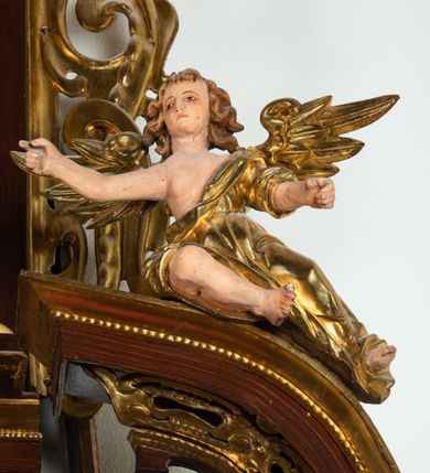 Zdjęcie nr 16: Ołtarz architektoniczny, dwukondygnacyjny, jednoosiowy ze zwieńczeniem. Mensa prostopadłościenna, antepedium w kształcie leżącego prostokąta, flankowane dwoma kanelowanymi pilastrami. W polu płycina w kształcie leżącego prostokąta wypełniona symetryczną dekoracją z akantu na czerwonym tle z sercem przebitym mieczem pośrodku. Cokół nastawy ustawiony na jednym stopniu, pośrodku zdobiony płyciną w kształcie leżącego prostokąta o zaokrąglonych krótszych bokach, cokoły pod kolumnami dekorowane mniejszymi płycinami wypełnionymi dekoracją roślinną. Pierwsza kondygnacja ujęta parą kolumn dźwigających przerwane belkowanie z przyczółkami, po bokach dodatkowo flankowana uszami wykończonymi ornamentem małżowinowo-chrząstkowym. W polu głównym obraz Najświętsze Serce Jezusa. Po bokach nastawy dwie rzeźby: po prawej św. Kazimierz Królewicz, a po lewej św. Alojzy Gonzaga. Na przyczółkach usadzone dwie rzeźby aniołów z rozłożonymi szeroko rękami. Kolumny ustawione na tle prostokątnych płycin, z bazami, trzony gładkie, kapitele kompozytowe. Druga kondygnacja flankowana parą kolumn podtrzymujących wyłamane belkowanie. W polu, w ramie o kształcie stojącego prostokąta o ściętych narożach obraz św. Michała Archanioła. W zwieńczeniu promienista gloria z monogramem Chrystusa na czerwonym tle, obwiedzionym wieńcem z obłoków. Zwieńczenie ujęte po bokach uszami. Struktura malowana w kolorze naturalnego drewna, ornamentyka złocona, detale srebrzone i czerwone.
