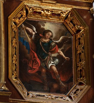 Zdjęcie nr 6: Ołtarz architektoniczny, dwukondygnacyjny, jednoosiowy ze zwieńczeniem. Mensa prostopadłościenna, antepedium w kształcie leżącego prostokąta, flankowane dwoma kanelowanymi pilastrami. W polu płycina w kształcie leżącego prostokąta wypełniona symetryczną dekoracją z akantu na czerwonym tle z sercem przebitym mieczem pośrodku. Cokół nastawy ustawiony na jednym stopniu, pośrodku zdobiony płyciną w kształcie leżącego prostokąta o zaokrąglonych krótszych bokach, cokoły pod kolumnami dekorowane mniejszymi płycinami wypełnionymi dekoracją roślinną. Pierwsza kondygnacja ujęta parą kolumn dźwigających przerwane belkowanie z przyczółkami, po bokach dodatkowo flankowana uszami wykończonymi ornamentem małżowinowo-chrząstkowym. W polu głównym obraz Najświętsze Serce Jezusa. Po bokach nastawy dwie rzeźby: po prawej św. Kazimierz Królewicz, a po lewej św. Alojzy Gonzaga. Na przyczółkach usadzone dwie rzeźby aniołów z rozłożonymi szeroko rękami. Kolumny ustawione na tle prostokątnych płycin, z bazami, trzony gładkie, kapitele kompozytowe. Druga kondygnacja flankowana parą kolumn podtrzymujących wyłamane belkowanie. W polu, w ramie o kształcie stojącego prostokąta o ściętych narożach obraz św. Michała Archanioła. W zwieńczeniu promienista gloria z monogramem Chrystusa na czerwonym tle, obwiedzionym wieńcem z obłoków. Zwieńczenie ujęte po bokach uszami. Struktura malowana w kolorze naturalnego drewna, ornamentyka złocona, detale srebrzone i czerwone.
