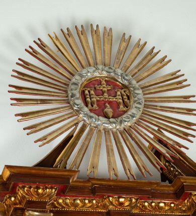 Zdjęcie nr 17: Ołtarz architektoniczny, dwukondygnacyjny, jednoosiowy ze zwieńczeniem. Mensa prostopadłościenna, antepedium w kształcie leżącego prostokąta, flankowane dwoma kanelowanymi pilastrami. W polu płycina w kształcie leżącego prostokąta wypełniona symetryczną dekoracją z akantu na czerwonym tle z sercem przebitym mieczem pośrodku. Cokół nastawy ustawiony na jednym stopniu, pośrodku zdobiony płyciną w kształcie leżącego prostokąta o zaokrąglonych krótszych bokach, cokoły pod kolumnami dekorowane mniejszymi płycinami wypełnionymi dekoracją roślinną. Pierwsza kondygnacja ujęta parą kolumn dźwigających przerwane belkowanie z przyczółkami, po bokach dodatkowo flankowana uszami wykończonymi ornamentem małżowinowo-chrząstkowym. W polu głównym obraz Najświętsze Serce Jezusa. Po bokach nastawy dwie rzeźby: po prawej św. Kazimierz Królewicz, a po lewej św. Alojzy Gonzaga. Na przyczółkach usadzone dwie rzeźby aniołów z rozłożonymi szeroko rękami. Kolumny ustawione na tle prostokątnych płycin, z bazami, trzony gładkie, kapitele kompozytowe. Druga kondygnacja flankowana parą kolumn podtrzymujących wyłamane belkowanie. W polu, w ramie o kształcie stojącego prostokąta o ściętych narożach obraz św. Michała Archanioła. W zwieńczeniu promienista gloria z monogramem Chrystusa na czerwonym tle, obwiedzionym wieńcem z obłoków. Zwieńczenie ujęte po bokach uszami. Struktura malowana w kolorze naturalnego drewna, ornamentyka złocona, detale srebrzone i czerwone.
