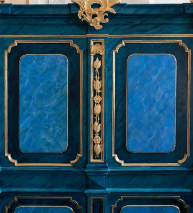 Zdjęcie nr 5: Dwie stalle o siedziskach obudowanych z przodu wybrzuszonymi ściankami z wazonami na pulpitach. Siedziska wybrzuszone z boku są ujęte falistymi poręczami, z plecami zdobionymi profilowanymi płycinami prostokątnymi o ściętych ćwierćkoliście narożach. Znajdujące się nad nimi wysokie zaplecki są ujęte pilastrami zdobionymi płycinami wypełnionymi wiciami liści i kwiatów z muszlami a z boku kampanuli, zwieńczone belkowaniem. W dwóch polach pomiędzy pilastrami zdwojone płyciny wyróżnione profilami w kształcie prostokątów o wyciętych ćwierćkoliście narożach.  Na belkowaniu trzy rokokowe kartusze i dwa płomieniste wazony. Polichromia imitująca jasno i ciemnoniebieską marmoryzację, ornamenty i profile złocone.  

Dwie stalle bez obudowy i wysokich zaplecków na falistych nogach, z których zewnętrzne poprzedzone lwimi łapami, z falistymi poręczami i prostymi oparciami zwieńczonymi gzymsem. Oparcie podzielone na trzy pola oddzielone żłobkowaniami i rautami nad nimi i wypełnione profilowanymi, kwadratowymi płycinami o ściętych ćwierćkoliście narożach.       