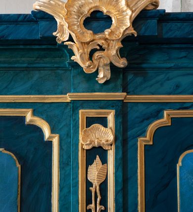 Zdjęcie nr 7: Dwie stalle o siedziskach obudowanych z przodu wybrzuszonymi ściankami z wazonami na pulpitach. Siedziska wybrzuszone z boku są ujęte falistymi poręczami, z plecami zdobionymi profilowanymi płycinami prostokątnymi o ściętych ćwierćkoliście narożach. Znajdujące się nad nimi wysokie zaplecki są ujęte pilastrami zdobionymi płycinami wypełnionymi wiciami liści i kwiatów z muszlami a z boku kampanuli, zwieńczone belkowaniem. W dwóch polach pomiędzy pilastrami zdwojone płyciny wyróżnione profilami w kształcie prostokątów o wyciętych ćwierćkoliście narożach.  Na belkowaniu trzy rokokowe kartusze i dwa płomieniste wazony. Polichromia imitująca jasno i ciemnoniebieską marmoryzację, ornamenty i profile złocone.  

Dwie stalle bez obudowy i wysokich zaplecków na falistych nogach, z których zewnętrzne poprzedzone lwimi łapami, z falistymi poręczami i prostymi oparciami zwieńczonymi gzymsem. Oparcie podzielone na trzy pola oddzielone żłobkowaniami i rautami nad nimi i wypełnione profilowanymi, kwadratowymi płycinami o ściętych ćwierćkoliście narożach.       