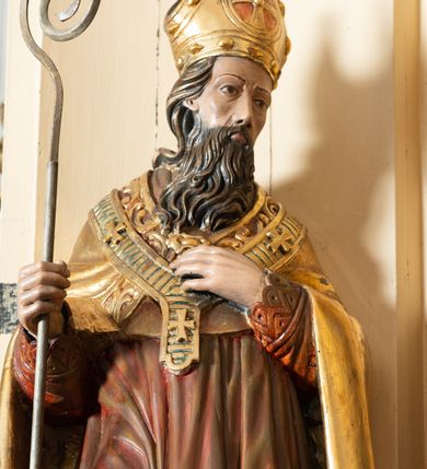 Zdjęcie nr 4: Przyścienna, jednokondygnacyjna, jednoosiowa nastawa ze zwieńczeniem uzyskała strukturę architektoniczną. Stipes ołtarzowy z drewnianą mensą z portatylem wykonano w kształcie sarkofagowym, ustawiając go na wysokim, fazowanym postumencie. Na nim znalazło się prostopadłościenne tabernakulum z obłym frontem udekorowanym prostokątnymi drzwiczkami zamkniętymi u góry nadwieszonym łukiem odcinkowy. Ich pole wypełnia płaskorzeźbione przedstawienie stojącego baranka apokaliptycznego. Całość wieńczy profilowany gzyms korrnujuacy utworzony z dwóch antetycznych wolut. Retabulum wsparto na dwuczęściowym, wysokim cokole. Kondygnację ujęto ustawionymi pod kątem opilastrowanymi, wklęsłymi filarami, przed którymi znalazła się para ustawionych pod kątem kolumn o kapitelach kompozytowych, usteweionyuch na postumentach o bokach dekorowanych prostokątnymi płycinami obramienionymi profilowanymi ramkami. Podpory dźwigają wyłamane imposty połączone ze sobą gzymsem. Na nim wsparto dwa falujące przyczółki, na których siedzi para putt. W polu kondygnacji umieszczono obraz Ukrzyżowania ujęty ramą w kształcie stojącego prostokąta zamkniętego u góry łukiem odcinkowym. Ponad nim na osi nastawę przepruto oculusem otwierającym się na okno witrażowe na wysokości przerwanego belkowania. Zwieńczenie ołtarza uzyskało kształt leżącego prostokąta o wklęsłych bokach utworzonych ze spływów wolutowych podtrzymujących profilowany gzyms koronujący powstały z dwóch antytetycznych wolut. W polu zwieńczenia umieszczono obraz św. Tytusa ujętego w fantazyjną ramę. Strukturę polichromowano na czarno. Głowice pilastrów i kapitele kolumn wyzłocono podobnie jak profile i obramowania. Rzeźby aniołków uzyskały naturalistyczną polichromię ze złoconymi przepaskami.   