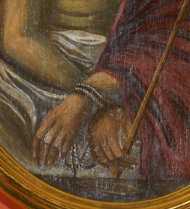 Zdjęcie nr 4: Obraz w kształcie stojącego owalu z przedstawieniem Chrystusa w typie Ecce Homo. Zbawiciel został ukazany w półpostaci, z rękami skrzyżowane przed sobą, związanymi i głową wzniesioną delikatnie w górę. Ma trójkątną twarz, szeroko otwarte oczy, uniesiony wzrok, wąski nos i usta. Twarz okala ciemny zarost, włosy opadają na barki i plecy, na głowie gruba korona cierniowa. Chrystus ma nagi tors i podkreślone żebra. Brzuch osłania biała tkanina, prawy bark i lewą rękę czerwony płaszcz. W lewej ręce trzyma trzcinę. Tło jednolite, ciemne, delikatnie rozjaśnione wokół głowy. 