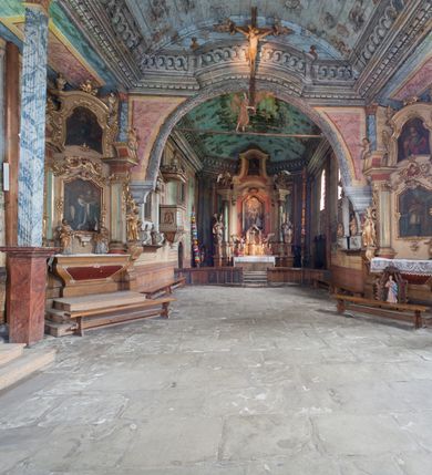 Zdjęcie nr 7: Kościół drewniany o konstrukcji zrębowej, elewacje jednolite, szalowane gontem. Wieża oraz kruchty zachodnia i południowa o konstrukcji słupowo-ramowej, kruchty szalowane deskami. Więźba dachowa drewniana, krokwiowa. Budynek na kamiennym podmurowaniu. 
Kościół orientowany, jednonawowy, nawa na rzucie prostokąta, prezbiterium węższe, wydłużone, zakończone trójbocznie. Do północnej ściany prezbiterium przylega zakrystia o wschodniej ścianie skośnej, będącej przedłużeniem bocznej ściany apsydy. 
Przy zachodniej ścianie nawy wieża na planie zbliżonym do kwadratu o wtórnym podziale na sale wystawiennicze (w przyziemiu wieży muzeum). Przy nawie od południa i przy wieży od frontu kruchty na planie kwadratu. 
Pomiędzy nawą a prezbiterium otwór tęczowy. 
Wnętrze nawy i prezbiterium nakryte pozornym sklepieniem kolebkowym, z zaskrzynieniami w nawie, podpartymi filarami o żłobkowanych trzonach, na cokołach, po trzy z każdej strony. Skrajem zaskrzynień nawy oraz górą ścian prezbiterium biegnie dekoracyjny gzyms drewniany, podparty w węgłach apsydy prezbiterialnej żłobkowanymi pilastrami. Łuk tęczowy półkolisty, wsparty na drewnianych konsolach. Otwory drzwiowe o prostokątnym wykroju zamknięte drzwiami obitymi deskami z metalowymi okuciami z prezbiterium do zakrystii, z nawy do kruchty południowej i z nawy do wieży. Okna w formie stojącego prostokąta zamkniętego łukiem odcinkowym, dwa w południowej ścianie prezbiterium, a w północnej dwa ślepe oraz cztery pary okien w północnej i południowej ścianie nawy. Na zamknięciu prezbiterium okulus z witrażem. Parapet chóru muzycznego w zachodniej części nawy, wsparty na dwóch drewnianych filarach, z wejściem z nawy po drabiniastych schodach z balustradą. Ściany i sklepienia pokryte polichromią z iluzjonistyczną architekturą i scenami figuralnymi. Posadzka kamienna.
Elewacja frontowa jednoosiowa. Na osi wejście do kruchty zachodniej. Korpus wieży o pochyłych ścianach, silnie zwężających się ku górze, zwieńczonych izbicą, ozdobioną u dołu koronką w formie zębów z frędzlami. Ściany kościoła, oprócz zakrystii i krucht szalowanych deskami, osłonięte rzędami gontów i opatrzone u dołu fartuchami. Na elewacji wschodniej ogrójec. 
Dach wyniosły, wspólny dla nawy i prezbiterium, hełm wieży cebulasty z latarnią, a w połowie długości dachu, nad nawą, wbudowana wieżyczka na sygnaturkę, wszystko kryte gontem. Kruchty nakryte osobnymi daszkami hełmowymi, baniastymi, krytymi gontem. 

Wokół kościoła rośnie starodrzew. Plac zamknięty kamiennym murem nakrytym drewnianym daszkiem dwuspadowym z 2 bramami i z 14 wieżyczkami (kapliczki-stacyjki) nakrytymi daszkami drewnianymi czterospadowymi. 