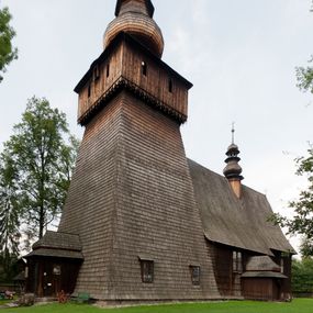 Zdjęcie nr 1: Kościół drewniany o konstrukcji zrębowej, elewacje jednolite, szalowane gontem. Wieża oraz kruchty zachodnia i południowa o konstrukcji słupowo-ramowej, kruchty szalowane deskami. Więźba dachowa drewniana, krokwiowa. Budynek na kamiennym podmurowaniu. 
Kościół orientowany, jednonawowy, nawa na rzucie prostokąta, prezbiterium węższe, wydłużone, zakończone trójbocznie. Do północnej ściany prezbiterium przylega zakrystia o wschodniej ścianie skośnej, będącej przedłużeniem bocznej ściany apsydy. 
Przy zachodniej ścianie nawy wieża na planie zbliżonym do kwadratu o wtórnym podziale na sale wystawiennicze (w przyziemiu wieży muzeum). Przy nawie od południa i przy wieży od frontu kruchty na planie kwadratu. 
Pomiędzy nawą a prezbiterium otwór tęczowy. 
Wnętrze nawy i prezbiterium nakryte pozornym sklepieniem kolebkowym, z zaskrzynieniami w nawie, podpartymi filarami o żłobkowanych trzonach, na cokołach, po trzy z każdej strony. Skrajem zaskrzynień nawy oraz górą ścian prezbiterium biegnie dekoracyjny gzyms drewniany, podparty w węgłach apsydy prezbiterialnej żłobkowanymi pilastrami. Łuk tęczowy półkolisty, wsparty na drewnianych konsolach. Otwory drzwiowe o prostokątnym wykroju zamknięte drzwiami obitymi deskami z metalowymi okuciami z prezbiterium do zakrystii, z nawy do kruchty południowej i z nawy do wieży. Okna w formie stojącego prostokąta zamkniętego łukiem odcinkowym, dwa w południowej ścianie prezbiterium, a w północnej dwa ślepe oraz cztery pary okien w północnej i południowej ścianie nawy. Na zamknięciu prezbiterium okulus z witrażem. Parapet chóru muzycznego w zachodniej części nawy, wsparty na dwóch drewnianych filarach, z wejściem z nawy po drabiniastych schodach z balustradą. Ściany i sklepienia pokryte polichromią z iluzjonistyczną architekturą i scenami figuralnymi. Posadzka kamienna.
Elewacja frontowa jednoosiowa. Na osi wejście do kruchty zachodniej. Korpus wieży o pochyłych ścianach, silnie zwężających się ku górze, zwieńczonych izbicą, ozdobioną u dołu koronką w formie zębów z frędzlami. Ściany kościoła, oprócz zakrystii i krucht szalowanych deskami, osłonięte rzędami gontów i opatrzone u dołu fartuchami. Na elewacji wschodniej ogrójec. 
Dach wyniosły, wspólny dla nawy i prezbiterium, hełm wieży cebulasty z latarnią, a w połowie długości dachu, nad nawą, wbudowana wieżyczka na sygnaturkę, wszystko kryte gontem. Kruchty nakryte osobnymi daszkami hełmowymi, baniastymi, krytymi gontem. 

Wokół kościoła rośnie starodrzew. Plac zamknięty kamiennym murem nakrytym drewnianym daszkiem dwuspadowym z 2 bramami i z 14 wieżyczkami (kapliczki-stacyjki) nakrytymi daszkami drewnianymi czterospadowymi. 