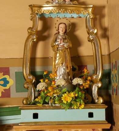 Zdjęcie nr 1: Feretron składa się z pełnoplastycznej rzeźby Najświętszej Marii Panny Niepokalanej ustawionej na prostopadłościennej skrzyni, nad którą wznosi się baldachim. Skrzynia ujęta przy krawędziach profilowanymi listwami. Ma otwory na drążki. Baldachim wsparty na czterech kabłąkach utworzonych z cęg, o wklęsło-wypukłym zarysie, z krawędziami obwiedzionymi profilowanymi listwami z podwieszonym stylizowanym lambrekinem. Na baldachimie rzeźbione przedstawienie z dwoma uskrzydlonymi główkami anielskimi pośród obłoków, ujmującymi gorejące serce w glorii. Podstawa i podniebienie baldachimu polichromowane w kolorze jasnoniebieskim, pozostałe elementy srebrzone i złocone.
Figura Marii ustawiona na kuli imitującej glob, ukazana frontalnie, z rękami złożonymi w geście modlitwy. Twarz ma prostokątną, o wąskich, małych oczach, prostym nosie i niewielkich ustach; okoloną długimi włosami, opadającymi na plecy. Ubrana jest w srebrzoną suknię, przepasaną w talii i złocony płaszcz zarzucony na ramiona i zawinięty z przodu postaci. Wokół jej głowy nimb z 12 gwiazdami. Polichromia ciała naturalistyczna. 


