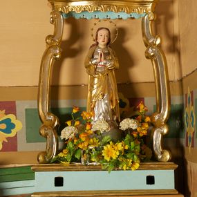 Zdjęcie nr 1: Feretron składa się z pełnoplastycznej rzeźby Najświętszej Marii Panny Niepokalanej ustawionej na prostopadłościennej skrzyni, nad którą wznosi się baldachim. Skrzynia ujęta przy krawędziach profilowanymi listwami. Ma otwory na drążki. Baldachim wsparty na czterech kabłąkach utworzonych z cęg, o wklęsło-wypukłym zarysie, z krawędziami obwiedzionymi profilowanymi listwami z podwieszonym stylizowanym lambrekinem. Na baldachimie rzeźbione przedstawienie z dwoma uskrzydlonymi główkami anielskimi pośród obłoków, ujmującymi gorejące serce w glorii. Podstawa i podniebienie baldachimu polichromowane w kolorze jasnoniebieskim, pozostałe elementy srebrzone i złocone.
Figura Marii ustawiona na kuli imitującej glob, ukazana frontalnie, z rękami złożonymi w geście modlitwy. Twarz ma prostokątną, o wąskich, małych oczach, prostym nosie i niewielkich ustach; okoloną długimi włosami, opadającymi na plecy. Ubrana jest w srebrzoną suknię, przepasaną w talii i złocony płaszcz zarzucony na ramiona i zawinięty z przodu postaci. Wokół jej głowy nimb z 12 gwiazdami. Polichromia ciała naturalistyczna. 


