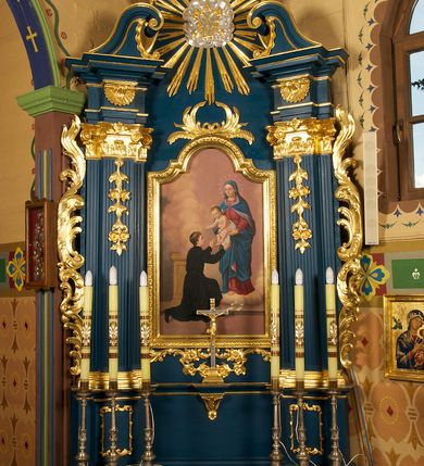 Zdjęcie nr 2: Ołtarz prostopadłościenny, z drewnianą mensą. W polu antepednium trzy przedstawienia: św. Michał Archanioł, Maria Niepokalanie Poczęta oraz św. Józef z Dzieciątkiem, każde ujęte złoconą ramą. 
Nastawa ołtarzowa jednoosiowa, jednokondygnacyjna ze zwieńczeniem, ustawiona na cokole. Kondygnacja nastawy ujęta zdwojonymi pilastrami o kapitelach kompozytowych  i kanelowanych trzonach, ustawionych pod kątem do środka. Ustawione na wyodrębnionych cokołach podpory dźwigają imposty oraz fragmenty przerwanego przyczółka. W polu środkowym nisza w formie stojącego prostokąta zamkniętego łukiem półkolistym nadwieszonym z uskokiem, ujęta profilowaną ramą. Zwieńczenie w formie zbliżonej do rombu, ujętego spływami wolutowymi, zamkniętego stykającymi się wolutami. W polu rzeźbione przedstawienie monogramu maryjnego na obłokach, ujęte glorią promienistą. Cokoły pilastrów dekorowane płycinami utworzonymi z ornamentu roślinnego. W partii trzonów zwisy kwiatowe, a impostów palmety. Rama pola środkowego ujęta od góry i dołu ornamentem roślinnym. Nastawa flankowana uszami utworzonymi z rocaille'u i ornamentu roślinnego. Struktura w kolorze granatowym; ornamentyka oraz profile złocone, obłoki srebrzone.