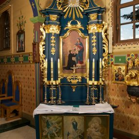 Zdjęcie nr 1: Ołtarz prostopadłościenny, z drewnianą mensą. W polu antepednium trzy przedstawienia: św. Michał Archanioł, Maria Niepokalanie Poczęta oraz św. Józef z Dzieciątkiem, każde ujęte złoconą ramą. 
Nastawa ołtarzowa jednoosiowa, jednokondygnacyjna ze zwieńczeniem, ustawiona na cokole. Kondygnacja nastawy ujęta zdwojonymi pilastrami o kapitelach kompozytowych  i kanelowanych trzonach, ustawionych pod kątem do środka. Ustawione na wyodrębnionych cokołach podpory dźwigają imposty oraz fragmenty przerwanego przyczółka. W polu środkowym nisza w formie stojącego prostokąta zamkniętego łukiem półkolistym nadwieszonym z uskokiem, ujęta profilowaną ramą. Zwieńczenie w formie zbliżonej do rombu, ujętego spływami wolutowymi, zamkniętego stykającymi się wolutami. W polu rzeźbione przedstawienie monogramu maryjnego na obłokach, ujęte glorią promienistą. Cokoły pilastrów dekorowane płycinami utworzonymi z ornamentu roślinnego. W partii trzonów zwisy kwiatowe, a impostów palmety. Rama pola środkowego ujęta od góry i dołu ornamentem roślinnym. Nastawa flankowana uszami utworzonymi z rocaille'u i ornamentu roślinnego. Struktura w kolorze granatowym; ornamentyka oraz profile złocone, obłoki srebrzone.