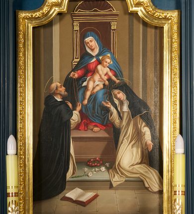 Zdjęcie nr 2: Obraz w formie stojącego prostokąta, przysłonięty szeroką, złoconą ramą zamkniętą od góry łukiem nadwieszonym z uskokiem. W centrum kompozycji Maria siedzi na architektonicznym tronie zwieńczonym muszlą. Tron ustawiony jest na stopniu i prostopadłościennym podeście. Zwrócona lekko w prawo, tronuje Maria z Dzieciątkiem na kolanach. Delikatnie pochyla głowę, prawą ręką wysuniętą w przód podaje różaniec św. Dominikowi, lewą przytrzymuje Dzieciątko. Maria ma twarz o młodzieńczych, delikatnych rysach, półprzymknięte oczy, wąski nos i niewielkie usta; wokół głowy złoty nimb. Jest ubrana w czerwoną suknię, biały welon oraz narzucony na niego niebieski płaszcz, który okrywa również ramiona i nogi, a zapięty jest pod szyją. Dzieciątko w pozycji siedzącej, zwrócone w lewą stronę, pochyla się ku św. Katarzynie. Prawą ręką podaje jej różaniec, lewą zakłada na jej głowę koronę cierniową. Dzieciątko ma owalną twarz o wyraźnych rysach, wysokie czoło, ciemne oczy, małe usta i nos; włosy krótkie, jasne, zaczesane do tyłu; za głową nimb kwadratowy. Jest przepasane białą tkaniną. W lewej, dolnej części kompozycji klęcząca postać św. Dominika ukazanego w całej postaci, zwróconego w trzech czwartych w prawo, ukazanego lekko od tyłu. Święty lewą rękę składa na piersi, prawą odbiera różaniec od Marii. Głowę ma uniesioną, twarz szczupłą, o ostrym profilu nosa, wzrok kieruje na Marię; włosy krótkie z tonsurą, nad głową złoty nimb. Jest ubrany w biały habit dominikański i czarny płaszcz z kapturem. Po prawej stronie obrazu postać klęczącej św. Katarzyny Sieneńskiej ukazanej w całej postaci, zwróconej w trzech czwartych w lewo, ze spuszczoną głową i rozłożonymi rękami. Prawą odbiera różaniec od Dzieciątka. Twarz świętej jest owalna, o dziewczęcych rysach i jasnej karnacji; oczy otwarte, nos długi o prostym profilu, usta wąskie; nad głową złoty nimb. Na stopniu, między klęczącymi świętymi kwiat lilii i wieniec z róż; na posadzce otwarta księga. Scena ukazana we wnętrzu z kamienną posadzką.