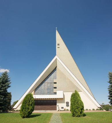 Zdjęcie nr 1: Budynek złożony z dwóch stopionych ze sobą brył, niższej o dwuspadowym dachu nakrywającym wnętrze prezbiterium i nawy oraz ostrosłupa wieży wpisanego w fasadę. Od strony prezbiterium dostawiona nieregularna bryła, niższa od kościoła, nakryta dwuspadowym dachem, mieszcząca zakrystię i kaplice Matki Boskiej. Połać dwustadowego dachu o nieregularnym, zygzakowatym konturze krawędzi, odsłaniającej przeszklone ściany, a miejscami sięgająca ziemi. Trójkątna w przekroju fasada z wieżą wpisaną w jej prawą połowę; lewa zaś w górnej połowie wypełniona witrażem, zamkniętym u dołu balkonem, nakrywającym przedsionek z wejściem do świątyni. Zewnętrzne elewacje kościoła pokryte są okładziną z wapienia pińczowskiego

Trójkątne w przekroju wnętrze podzielone na trzy nawy filarami. Prezbiterium zamknięte ścianą z wydzielonym trójkątem ołtarza głównego, złożonego z dwóch ścian pokrytych okładziną ceramiczną ustawionych pod kątem rozwartym, z otworem u szczytu na okno. Po przeciwnej stronie wnętrza wejście na wieżę i parapet chóru muzycznego. Na zakończeniu lewej nawy wejście do kaplicy Matki Boskiej, na zakończeniu prawej nawy zaaranżowana kaplica bł. Anieli Salawy. Ściany boczne całkowicie przeszklone; połowę przestrzeni fasady wypełnia witraż o polu w formie trójkąta o kącie prostym. W kaplicy Matki Boskiej otwory w formie szczelin oświetlające wnętrze umieszczone nieregularnie w polu ściany. 




